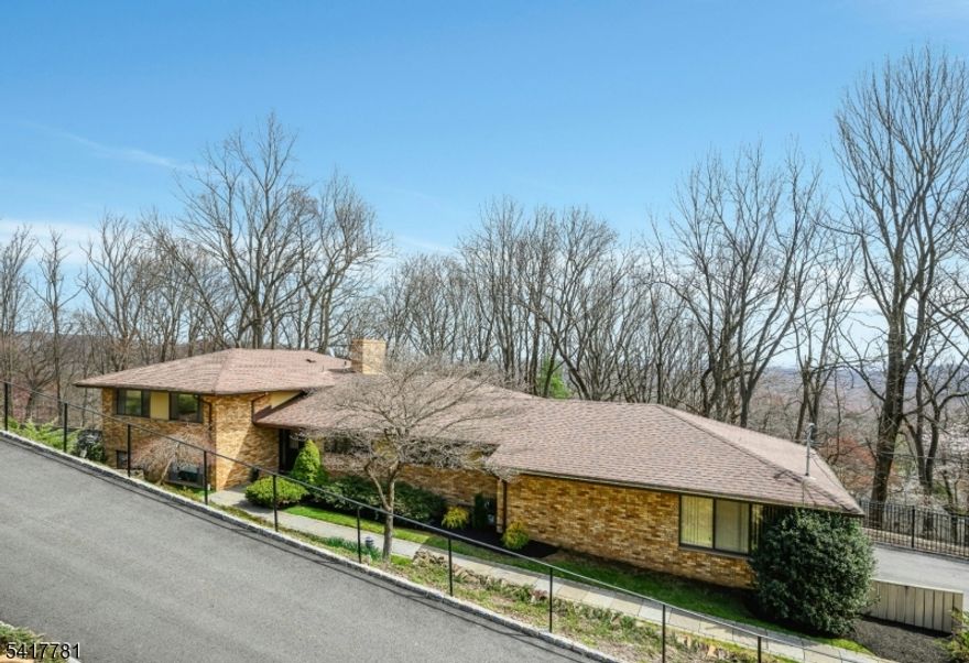 This custom home is filled with amazing natural light & offers beautiful views & exceptional privacy. Nestled in a serene setting, it features hardwood flooring throughout most of the home and beautifully renovated baths. The inviting living room showcases a wood-burning fireplace, while the open living and dining room layout creates a seamless flow for everyday living and entertaining, with direct access to an expansive deck-perfect for enjoying the surrounding views. The spacious eat-in kitchen is both stylish and functional, featuring wood cabinetry, granite countertops, some stainless appliances including a refrigerator, dishwasher, double ovens, and a gas cooktop--Perfect for everyday living and entertaining alike. A generous walk-in pantry adds storage & convenience, keeping everything beautifully organized and within reach. With five bedrooms, a dedicated office, and three and one-half updated baths, the layout is both spacious and versatile, including the potential for a guest suite with a bedroom & full bath on a separate living level. The family room provides direct access to the patio, extending your living space outdoors. A daylight basement with high ceilings and a walk-out offers excellent future potential for additional living space & recreation.. Completing the home is an oversized garage, along with an expansive deck and patio-perfect for relaxing & entertaining. Equipped for modern living, the home  includes a generator.  Move-In & Enjoy