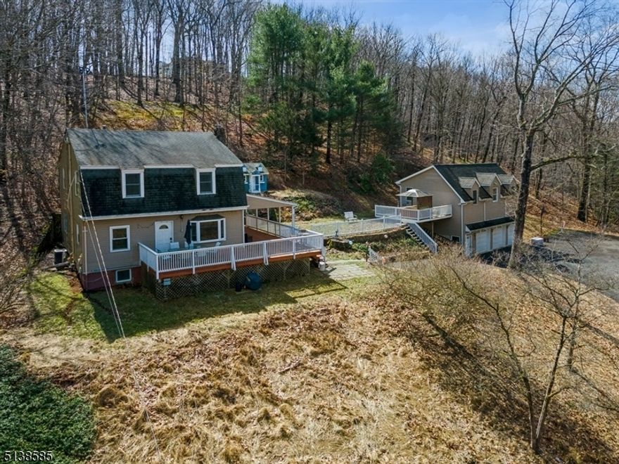 Private home w/mountain views! Spacious Colonial home 5BD, 2BTH and a separate 3-car garage w/an enormous rec-room above it is nestled on a peaceful wooded ridge in Mendham. Set amongst nature on over 1 1/2 private acres, yet with every convenience at your fingertips, this home is near Blue Ribbon Twp. schools, shopping & dining in the historic downtown, major hwys & about 15 min to the Midtown Direct train to NYC. Walking distance to Raritan River, Patriot's Path, a local farm & the infamous Black Horse Pub. Taking full advantage of its hilltop location, this home has been built to showcase the sweeping treetop & mountain views. A large deck spans the length of the house creating the perfect setting to entertain guests or enjoy the sunset. Featuring gracefully arched doorways, crown molding & trimwork details, the interior flows effortlessly from the spacious LR w/a rustic stone fireplace to the formal DR. The bright, recently redone kitchen is clad w/granite counters, SS appliances, crisp white cabinetry, a center island & French doors to the deck. A 1st floor BD w/a cedar lined closet and full en suite BTH completes this level. On the 2nd floor are 4 generous-sized BD & a hallway BTH. The partially finished basement offers a rec-room, workshop & laundry room. There is also a spacious recreation room above the three-car garage which features another deck, providing additional beautiful views & offering the potential as a personal retreat or studio w/plenty of storage.