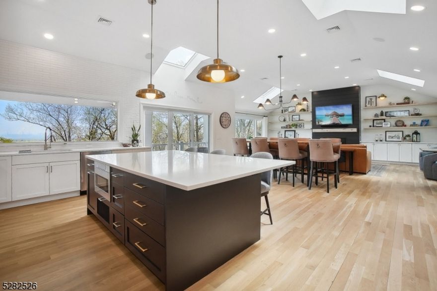 Welcome to your new home, where each day is painted with the vibrant hues of the city skyline. Nestled in the heart of Upper Montclair, this stunning residence offers more than just a place to live it's a front-row seat to a living canvas of urban beauty. Perched atop a secluded wooded lot, this nearly 3000 sqft raised ranch boasts 3 bedrooms, 3 full bathrooms, and a total renovation that has elevated it to the height of luxury living. As you step inside, a spacious foyer welcomes you, with a sitting and family room to the left, as well as a bathroom, access to the garage, a laundry room and plenty of storage options. As you make your way upstairs your eyes are drawn to a grand cathedral window, signaling that something breathtaking awaits you.  Once upstairs you are greeted by panoramic city views,  high ceilings, abundance of natural light and radiant heat wood flooring. The open floor plan flows seamlessly from the kitchen into the living & dining areas, which are anchored by a cozy fireplace.  All bedrooms are conveniently located on the same floor. The primary bedroom boasts its own ensuite bathroom, complete with dual closets, and a door leading to the front balcony, that offers eastern views. Whether you enjoy the tranquility of the heated front balcony, the privacy of the back patio, or the benefits of the open floor plan, this home provides multiple spaces for entertaining and the panoramic views that provide the perfect backdrop for every occasion.