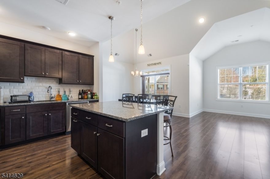 MOVE-IN READY LITTLE FALLS CONDO WITH OPEN FLOOR PLAN & NUMEROUS UPGRADES! Welcome to a 2 Bed / 2.1 Bath townhome in a well-maintained 8-year-old community minutes from Little Falls train (with free parking!), Routes 80 & 46, as well as shops & dining in Upper Montclair. This 3-level home enjoys sheltered entry & indoor access to attached single-car garage. Main living area has a wonderful open floor plan featuring vaulted ceilings, wide-plank hardwood floors throughout, sliding French doors from the Dining area to a balcony, sleek modern gas fireplace under wall-mount TV in the Living Room, & an upgraded modern Eat-in Kitchen in the center of it all! Kitchen boasts dark-stained wood cabinetry, granite countertops, subway tile backsplash, SS appliances, including gas range, microwave & dishwasher, & an island that seats three. A Half Bath, Pantry Closet & Coat Closet round out this level for easy entertaining & relaxing. Adjourn to the top level to find an open Family Room/Loft with a closet, Laundry Room, & an updated Full Hall Bath with a tub/shower combo. Primary Suite offers private oasis with double windows, pull-down wall-mount TV for easy viewing, large Walk-in Closet with attic access for storage, & spacious ensuite Bathroom with 2-sink granite-topped vanity & walk-in shower with frameless glass. Second Bedroom features double-door closet & wall-mount TV, making three TVs total included with sale! Modern living is easy at 104 Autumn Ct!