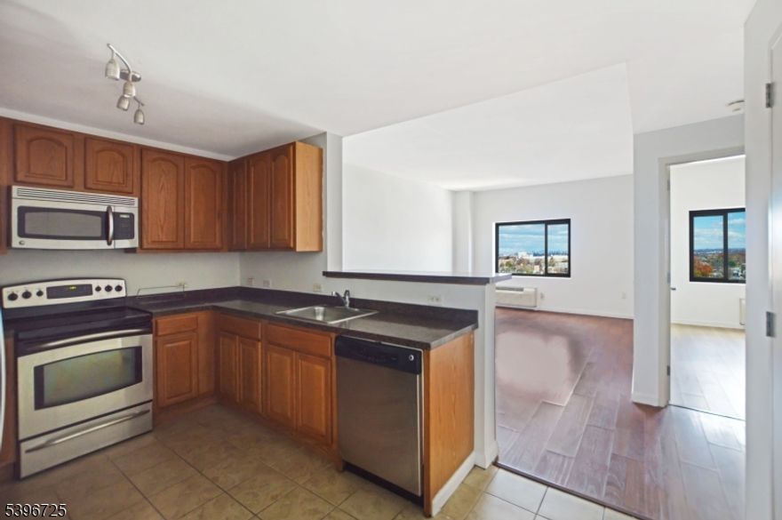 Live above it all at Skyview, in this bright 1 bed / 1 bath condo on the 12th floor of 1 Carriage City Plaza with sweeping NYC-facing views. At roughly 810 sq ft, the home offers a spacious living/dining area, a full kitchen with stainless steel appliances, new recessed lights, and the convenience of an in-unit washer/dryer. Unit is freshly painted and move-in ready.  Skyview is a concierge building with a 24-hour fitness center, secure key-fob entry, rooftop terrace with lounge seating and BBQ grills, resident's lounge, package room and on-site restaurant/lounge at Watt Hotel and retail. Garage parking is available on-site for an additional $120/month. Located in the heart of downtown Rahway, you're directly across from the Rahway NJ Transit station offering frequent trains to New York Penn Station in low as 35 minutes, plus service south through New Jersey. Step outside to a walkable arts district with the Union County Performing Arts Center, coffee shops, breweries, and a wide range of restaurants all just a few blocks away. Perfect for commuters and anyone who wants condo living with an urban downtown vibe and easy access to NYC. Easy to show and available immediately.