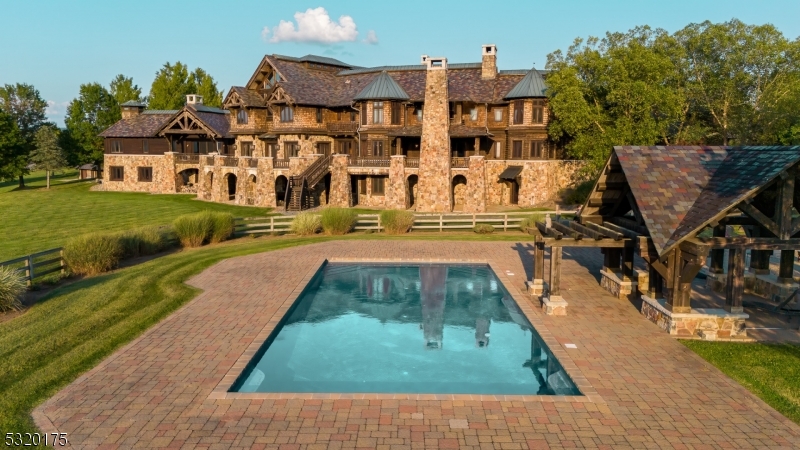 Experience the ultimate in luxury and privacy with this extraordinary 25,000 sq. ft. custom-built estate, set on 125 acres of breathtaking countryside in Hunterdon County. Built in 2003, this estate offers 35 beautifully designed rooms, including 7 bedrooms, 7 full baths, and 3 half baths. The expansive interior is highlighted by vaulted ceilings, rich wood finishes, and oversized windows, seamlessly blending elegance and comfort. A chef's kitchen with top-tier appliances, multiple living and dining areas, a gym, media room, theater, and indoor basketball and squash courts cater to both relaxation and entertainment. The lower level features a private spa, wine cellar, and more spaces for leisure. Outside, the estate boasts resort-style living with a pristine pool, tennis court, and expansive patio for outdoor gatherings. Historic and modern barns, a utility building, a vineyard, and solar panels further enhance the property's charm and sustainability. Perfect for equestrian use, a winery expansion, or as a luxurious private retreat, this estate is just over an hour from New York City and Philadelphia. This is a rare opportunity to own a magnificent estate offering unmatched luxury, privacy, and potential. Check all links under Media- Document sec for Property Details.