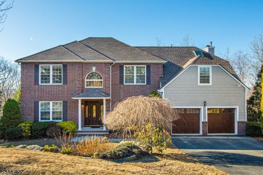 This upgraded Center Hall Colonial on a cul-de-sac offers a spacious layout with modern amenities. A two-story foyer leads to an open-concept kitchen and great room with hardwood and porcelain tile flooring. The kitchen features 42  cabinets, granite countertops, a center island with seating, recessed lighting, and a separate eating area. Stainless steel appliances complete the space. The great room boasts a two-story cathedral ceiling, two venting skylights, Andersen doors and windows, a bay window, and transom windows framing a floor-to-ceiling Montana top rock stone wood-burning fireplace. The primary suite includes an 11-foot tray ceiling, LED crown molding, recessed lighting, and a two-sided gas fireplace with a real ledgestone veneer and limestone hearth. French doors open to a sitting room with a Juliet balcony overlooking the great room. The primary bath features heated flooring, a frameless glass spa shower, and a heated jetted jacuzzi tub. Additional highlights include central air, an irrigation system, a large custom deck and patio, a brick front, a full walk-out basement, and city utilities. Located in a neighborhood with sidewalks, this home blends comfort and convenience in a prime setting.