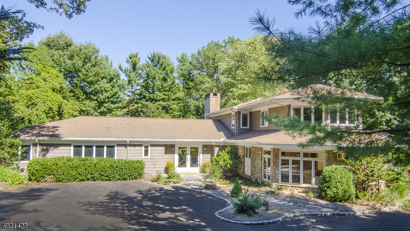Fabulous expansive 17 room mid-century set on 1.5 acres of lush property waiting for your decorating touch! Gourmet EIK, hexagonal family room, private 1st floor master suite; 5 more bedrooms & baths. Must see special features include parquet wood floors, lighted display niches, recessed gallery lighting, floor-to-ceiling picture windows w/ ever changing seasonal views, wood-burning fireplace w/ raised slate hearth, state of the art spacious kitchen w/ the very best in appliances, granite center island & peninsula between cooking area & the breakfast room; adjacent laundry room. 1st floor in-law suite consists of kitchenette sitting room, bedroom, full bath & powder room. Finished lower level w/ vaulted ceiling.  A prime location offering the best of NJ schools, premium shopping & direct commute to NYC trains