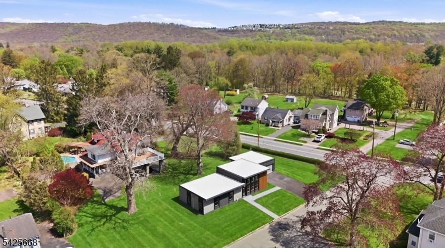 This new-construction contemporary ranch showcases a sleek, modern design with a flat roofline and a striking blend of materials that create both warmth and sophistication. The exterior features gray vertical and horizontal siding accented with natural wood tones, adding depth and texture to the facade. At the center, expansive floor-to-ceiling black-framed windows make a bold architectural statement, flooding the interior with natural light and highlighting the home's clean, modern aesthetic. Inside, the home offers 3 bedrooms and 2 bathrooms, along with a detached garage that includes a versatile flex-space ideal for an office, playroom, studio, or recreation room. The kitchen is beautifully finished with stainless steel appliances, granite countertops, gray cabinetry, a center island, and excellent workspace. Stunning natural light fills every room, enhanced by recessed lighting and vinyl plank flooring throughout. The primary bedroom features generous closet space and a well-appointed en-suite bathroom with a walk-in shower. Both bathrooms are tastefully designed with modern finishes. Step outside to a welcoming patio, perfect for enjoying your morning coffee or relaxing outdoors. Located just a short walk to town, you'll enjoy convenient access to great shopping, restaurants, and entertainment including the renowned Centenary Stage Company. Additional highlights include public water, public sewer, and natural gas, offering comfort and ease of maintenance.