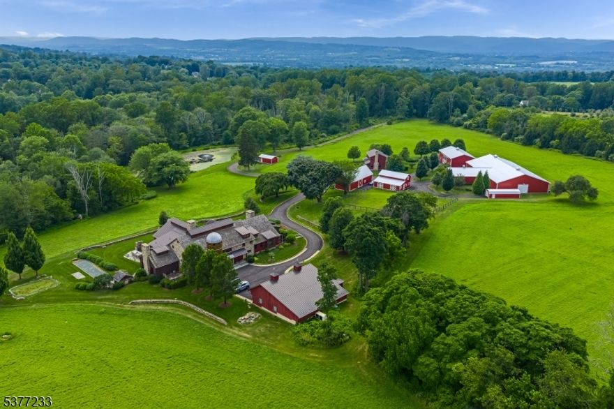 Discover an unparalleled blend of historic grandeur and modern luxury at Double G Farm, a 62+ acre estate rooted in 1850 history. The centerpiece is a museum-quality 1800s barn forming the great room, original beams & panels extend three stories high with a masterful expansion of over 13,000 sq ft that mimics the original stone bank barn's architecture. Exquisite craftsmanship, authentic wood beams, stone accents, cupola ceiling, & steel railings create a unique aesthetic. Sun-filled spaces, select wood flooring, volume ceilings, creative window placements, Venetian walls show impeccable attention to detail. Intelligently designed main level boasts a flawless flow between rooms and features a convenient 1st-floor master suite. 35'+ silo housing custom staircase, leading to BRs, lofted library, & balcony. The lower level is a haven for entertainment and relaxation, enjoy a spacious family room, an 11-stool bar, indoor saltwater pool with Nano doors opening to outdoor kitchen, chef's kitchen, wine cellar, dog grooming room, game room, and 3-car garage. Every detail accounted for w/ amenities including Control 4 Smart Home automation, elevator, dumbwaiters, security cameras, generators, bocce court, & wide radius driveways. Outbuildings: detached 12+-car garage, 4BR guest house, climate controlled EVENT BARN, a 4-stall barn, 2 other full barns, smokehouses & storage sheds.  A truly unique opportunity to own a piece of history enhanced with every modern luxury imaginable.