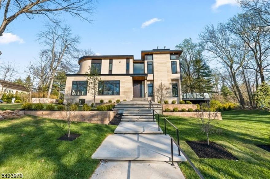 9 Farbrook Dr is a stunning modern custom home by local SH Builder, showcasing the thoughtful design and craftsmanship behind many exceptional homes. Set on over half an acre, the home features a striking exterior featuring sintered travertine slabs and designer tile finishes. A dramatic 10-foot front door opens to a light-filled interior featuring 10-foot ceilings on both the first and second floors, a floating staircase with custom glass railing, and an open floor plan designed for modern living. Over 6,700 sq. ft, this 6-bedroom, 6 full bath, 1 powder room home is designed for both elegant entertaining and everyday living. The main level includes a formal living room, private office, first-floor guest suite, spacious family room with a linear gas fireplace, custom kitchen, and dining room with built-ins. A wall of glass opens to a large deck with glass railing, creating seamless indoor-outdoor living. Upstairs are four en-suite bedrooms with walk-in closets and heated bath floors, including a serene primary suite with a second gas fireplace. The walkout lower level features an additional bedroom and full bath, wine room, gym, and expansive recreation space opening to the backyard and potential future pool. Additional highlights include a two-car garage at kitchen level, a full-house automated lighting system controlled through a phone app, prewiring for future speakers, shades, audio, and TV, and close proximity to highly rated Deerfield School.