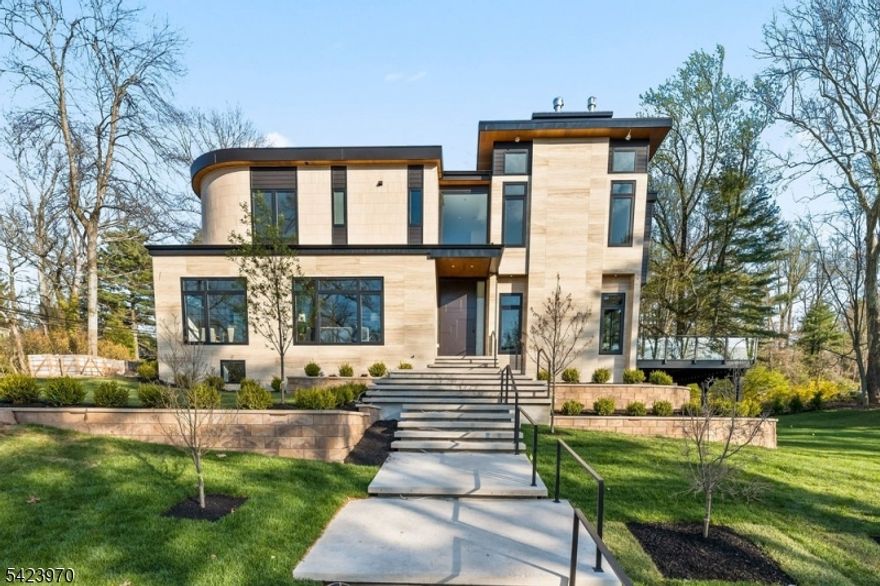 9 Farbrook Dr is a stunning modern custom home by local SH Builder, showcasing the thoughtful design and craftsmanship behind many exceptional homes. Set on over half an acre, the home features a striking exterior featuring sintered travertine slabs and designer tile finishes. A dramatic 10-foot front door opens to a light-filled interior featuring 10-foot ceilings on both the first and second floors, a floating staircase with custom glass railing, and an open floor plan designed for modern living. Over 6,700 sq. ft, this 6-bedroom, 6 full bath, 1 powder room home is designed for both elegant entertaining and everyday living. The main level includes a formal living room, private office, first-floor guest suite, spacious family room with a linear gas fireplace, custom kitchen, and dining room with built-ins. A wall of glass opens to a large deck with glass railing, creating seamless indoor-outdoor living. Upstairs are four en-suite bedrooms with walk-in closets and heated bath floors, including a serene primary suite with a second gas fireplace. The walkout lower level features an additional bedroom and full bath, wine room, gym, and expansive recreation space opening to the backyard and potential future pool. Additional highlights include a two-car garage at kitchen level, a full-house automated lighting system controlled through a phone app, prewiring for future speakers, shades, audio, and TV, and close proximity to highly rated Deerfield School.