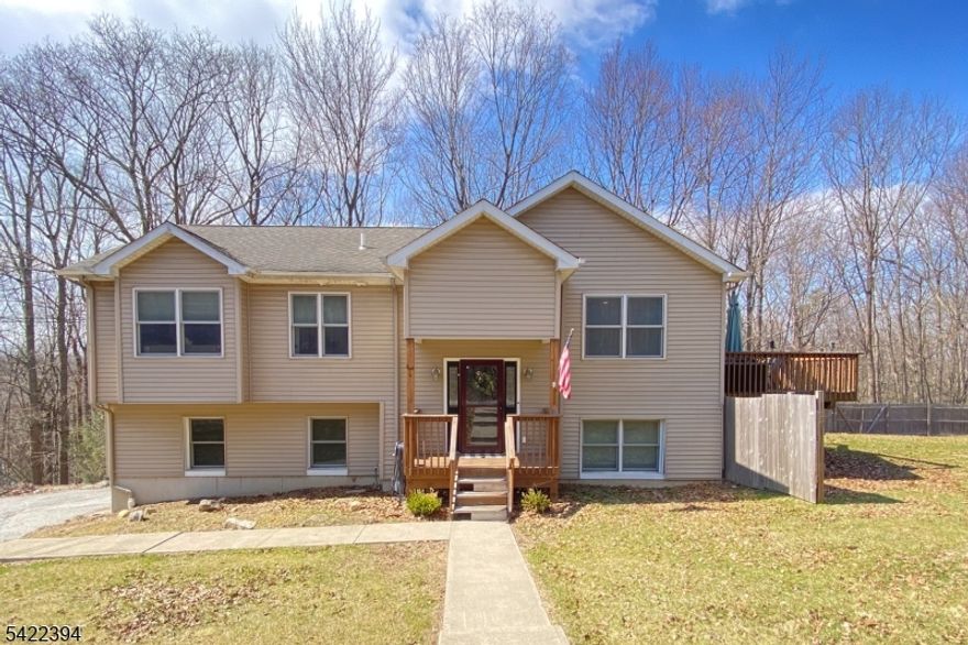 Turnkey 2006 bilevel set on a .7 acre private lot in Vernon, short drive to both Wawayanda State Park and Mountain Creek for year-round recreation. Also nearby NYS destinations including wineries. Upper level features hardwood floors throughout, with a bright living and dining area and slider to a deck overlooking the side and rear yard. Kitchen includes granite countertops, stainless appliances, and ample cabinetry. 3 bedrooms on this level, including a primary suite with full bath, plus an additional full hallway bathroom. Lower level offers a family room with newer vinyl flooring, built-in shelving suitable for office or library use, and flexible space for gym or media use. Direct access to a 2-car garage with additional storage area. Built in 2006 with a functional, balanced layout suited for buyers seeking space, privacy, and access to outdoor recreation..