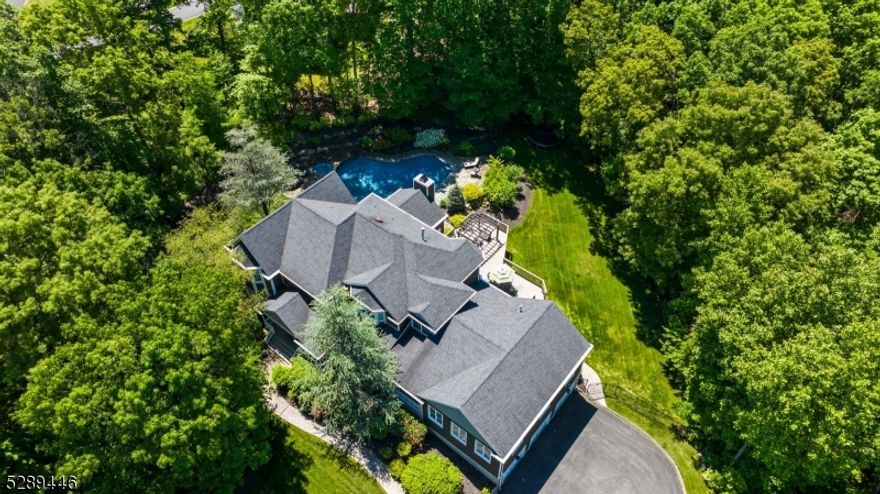 Discover this stunning turnkey custom colonial nestled on a quiet street in Montville Township. Set on a sprawling 2-acre lot, this exquisite home features a covered mahogany porch, a gunite saltwater heated pool & hot tub all surrounded by beautiful blue-stone & lush trees for ultimate privacy. Step inside to a grand two-story foyer with a wrought iron winding staircase & gleaming hardwood floors throughout. The family room boasts cathedral ceilings & a floor to ceiling stone wood-burning fireplace with access to the deck or pool. The gourmet eat-in kitchen is a conversation piece of its own. Boasting quartzite countertops, high-end appliances, center island with seating, coffee bar & a walk-in 1100-bottle temperature-controlled wine room. Entertain in style in the oversized great room flooded with natural sunlight, high ceiling or host gatherings in the formal living & dining room. The first floor also includes a bedroom, laundry room with sink & 1.5 baths. On the 2nd level, the primary suite offers tray ceilings, walk-in closet, loft, and a luxurious bathroom with dual vanities, soaking tub & walk-in shower. Two additional bedrooms, an office/bedroom & a main bath complete the upstairs. The lower level features a finished gym area, 3 car garage access, ample storage & a full house generator, ensuring comfort & convenience in every season. Home is located in Montville Twp. with a Boonton Twp. mailing address.