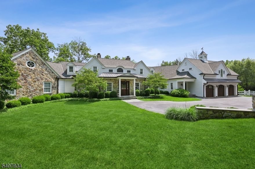 Set on nearly eight farm-assessed acres bordering Mendham and Peapack-Gladstone, Golden Acres Farm offers a blend of refined country living and amenities for the serious automobile enthusiast. Architect Patrick Burke designed the 6,103-square-foot residence that delivers privacy, craftsmanship, and functionality in equal measure. The main residence is thoughtfully designed for both everyday living and entertaining. A first-floor primary suite provides ease and comfort, featuring a fireplace, dual walk-in custom closets, and direct access to the rear grounds. The custom kitchen includes professional-grade appliances, a wood or gas fired pizza oven, dual dishwashers, steam oven, coffee bar, and a generous center island. The Great Room frames the pastoral views through multiple sets of French doors opening to the expansive terrace. Upstairs, two ensuite bedrooms and a private in-law suite with kitchen offer flexibility for guests. The walk-out lower level expands the living space with a recreation room, game room, gym with daylight, additional kitchen, office, and project room perfect for hobbies. An air conditioned vehicle barn accommodates approximately 15 cars with two vehicle lifts, a bathroom, office/den, and security system. A second barn provides multi-purpose storage for vehicles or animals. An in-ground heated saline pool, fenced rear yard, and a covered patio featuring a wood-burning fireplace and television are ideal for outdoor enjoyment.