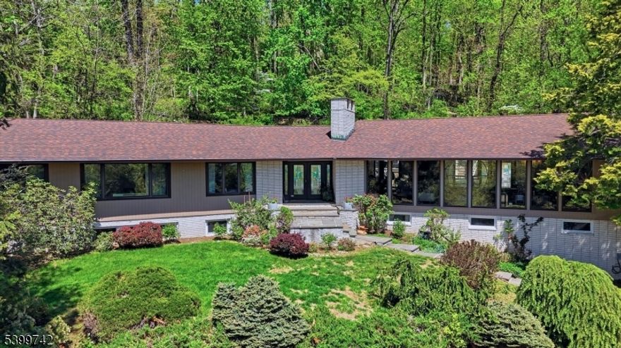 Tucked away on a private 0.57-acre wooded hillside, this 5 BR, 3 BA exceptional mid-century modern home offers a seamless blend of iconic design and resort-inspired living. The sun-filled interior features soaring vaulted ceilings with exposed beams and new 2026 European floor-to-ceiling windows and sliding doors that frame tranquil greenery. The open-concept living and dining areas flow effortlessly, anchored by rich wood accents and elegant architectural detailing. A chef?s kitchen with Miele/Sub-Zero appliances and radiant flooring, and newly updated designer bathrooms showcase stone composite tubs and premium finishes. The multi-tiered backyard is an entertainer?s dream, complete with an in-ground pool, hot tub and built-in professional-grade outdoor kitchen, and secluded patios. A fully finished lower level with a sauna, recreation room, a full bathroom and 2 guest bedrooms completes this unparalleled sanctuary just moments from top-rated schools and the Mid-Town Direct train.