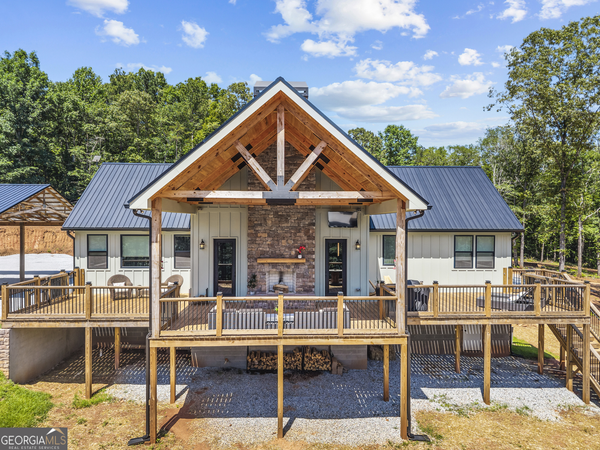 ***Open House: Saturday, 9/13 10-12pm***Welcome to your dream retreat! Nestled on 33 private acres, this beautifully updated 3-bedroom, 2-bath home offers the perfect blend of modern comfort and rustic charm. From the moment you walk in, you're greeted by soaring wood-beamed ceilings and an expansive open-concept layout that's made for gathering and entertaining. The heart of the home is the gourmet kitchen, featuring stainless steel appliances-including a dedicated ice maker-a massive island, breakfast bar, and eat-in dining area. Just off the kitchen, you'll find a thoughtfully designed mudroom complete with built-in laundry and a custom dog wash station-perfect for keeping things tidy after outdoor adventures.The kitchen flows seamlessly into the living room where a striking floor-to-ceiling stone fireplace creates a cozy and inviting atmosphere. The split-bedroom floor plan offers privacy and functionality. The spacious primary suite is filled with natural light from oversized windows and features a luxurious en-suite bath with dual vanities, a large walk-in shower, and generous walk-in closet. On the opposite side of the home, you'll find two additional bedrooms, each with large windows, and a beautifully updated full bath. Step outside to the massive back deck, complete with a second soaring stone fireplace, ideal for year-round entertaining. Whether you're enjoying sunshine or relaxing under the covered area, the space is designed for hosting and unwinding. A large carport is attached to an additional storage building/garage-perfect for all your tools, toys, and gear. And that's not all-- this property also features a 30x40 pole barn with power, a concrete slab, and lean-tos on both sides, offering even more storage or workspace. Plus, there's an additional well on the property for added utility and flexibility. For outdoor enthusiasts, this land is a true gem offering excellent hunting opportunities with an abundance of deer, turkey, and other local wildlife. Don't miss this rare opportunity to own a slice of paradise in Danielsville. This one-of-a-kind home checks every box-schedule your private showing today!