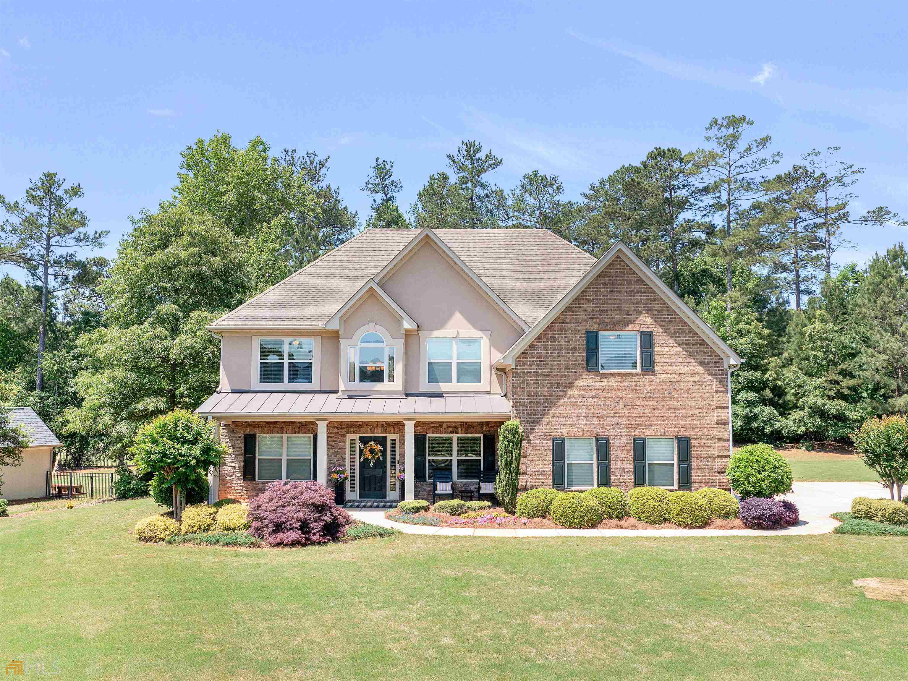 You do not have to be an avid golfer to enjoy the golf community lifestyle that this home can provide. Imagine yourself on the large owner's suite deck enjoying an early morning coffee or an evening glass of wine while you overlook the 4th hole on Georgia National Golf Course. This four-sided brick home is beautifully situated on a corner lot with lovely curb appeal. The multi-zone irrigation system is a convenient amenity for easy watering during the summer months. When you step into the grand entry, your eyes will be drawn to the doorway arches and executive trim. The entry is flanked by a formal dining room and formal living room that functions wonderfully as a home office. The kitchen offers a hospitable layout for entertaining with lots of storage. The two story family room is filled with natural light and is anchored by a welcoming fireplace. Just off the family room, there is one of TWO owner suites! The suite on the main offers views of the golf course and has an en suite bath (double vanity, tub and tiled shower). Upstairs, you will find three additional bedrooms that share a bathroom and the second owner's suite. The second owner's en suite bath features a double vanity, soaker tub and tiled shower. The oversized layout of this bedroom allows opportunity for an additional sitting area or temporary nursery. If front porch sitting is more your style, the covered porch is a great place to relax and wave at your friendly neighbors as they ride by on their evening golf cart ride.