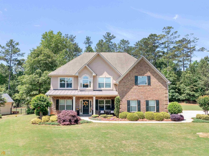 You do not have to be an avid golfer to enjoy the golf community lifestyle that this home can provide. Imagine yourself on the large owner's suite deck enjoying an early morning coffee or an evening glass of wine while you overlook the 4th hole on Georgia National Golf Course. This four-sided brick home is beautifully situated on a corner lot with lovely curb appeal. The multi-zone irrigation system is a convenient amenity for easy watering during the summer months. When you step into the grand entry, your eyes will be drawn to the doorway arches and executive trim. The entry is flanked by a formal dining room and formal living room that functions wonderfully as a home office. The kitchen offers a hospitable layout for entertaining with lots of storage. The two story family room is filled with natural light and is anchored by a welcoming fireplace. Just off the family room, there is one of TWO owner suites! The suite on the main offers views of the golf course and has an en suite bath (double vanity, tub and tiled shower). Upstairs, you will find three additional bedrooms that share a bathroom and the second owner's suite. The second owner's en suite bath features a double vanity, soaker tub and tiled shower. The oversized layout of this bedroom allows opportunity for an additional sitting area or temporary nursery. If front porch sitting is more your style, the covered porch is a great place to relax and wave at your friendly neighbors as they ride by on their evening golf cart ride.