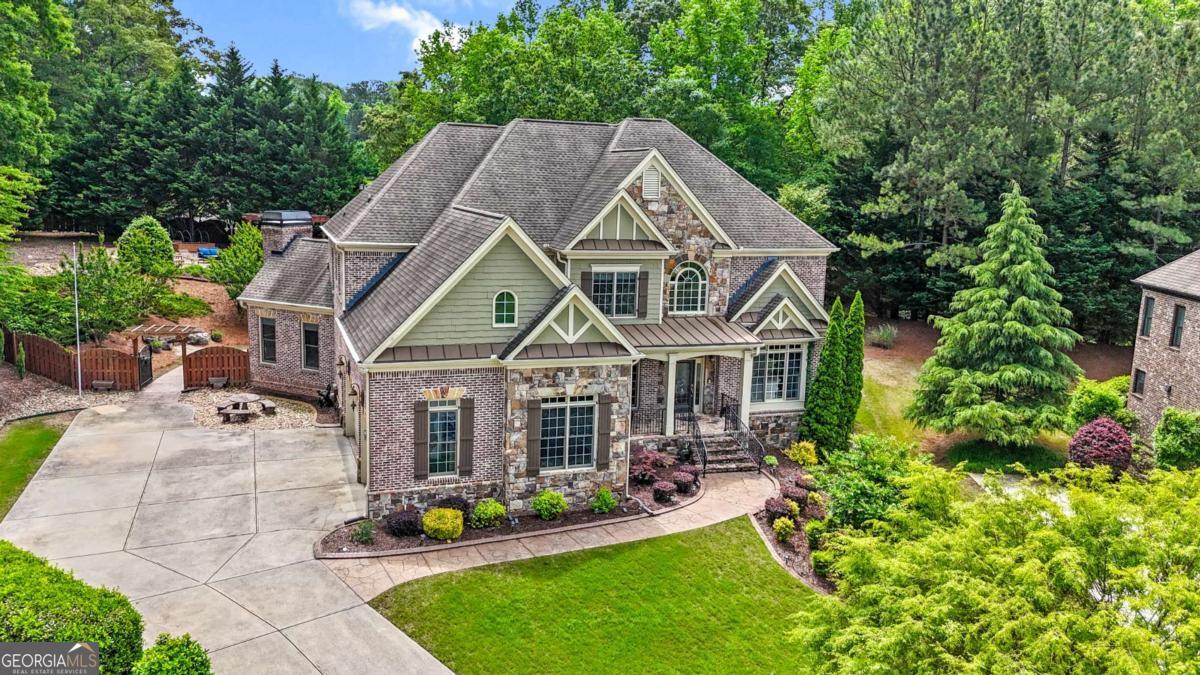 Tucked away on a quiet cul-de-sac, this beautifully crafted home offers refined living across three finished levels. Designed with high-end features including extensive trim work, crown molding, built-ins, gleaming hardwood floors, coffered ceilings, arched windows, and CAT5 wiring with central vacuum throughout. The gourmet kitchen is a chef's dream, featuring premium stainless steel appliances, Cambria countertops, a breakfast bar, wine rack, plate rack, abundant cabinetry, built-in desk, and generous serving space. A large breakfast area flows seamlessly into the cozy fireside keeping room - perfect for casual gatherings. The main level includes a guest bedroom and full bath, ideal for visitors or a home office. Upstairs, you'll find the luxurious master suite with a sitting area, fireplace, and an expansive walk-in closet. Three additional bedrooms, two full bathrooms, and a media room complete the upper level. The finished terrace level offers the same high-quality finishes and includes a spacious recreation room, bedroom, full bath, and multiple unfinished areas ready for customization or storage. Outdoor living is a true highlight of this home! Step out to the screened-in porch and enjoy the professionally landscaped backyard featuring a fireplace, multiple seating areas, walkways, a pergola, and a stunning 32-foot waterfall. There's even plenty of room to add a pool or enjoy lawn games. Located in a desirable community with top-notch amenities including a pool, clubhouse with catering kitchen, fitness center, tennis courts, and playground. Zoned for the brand-new Seckinger High School, this home truly has it all. Don't miss the chance to make this pristine, move-in-ready home yours - it's a must-see!