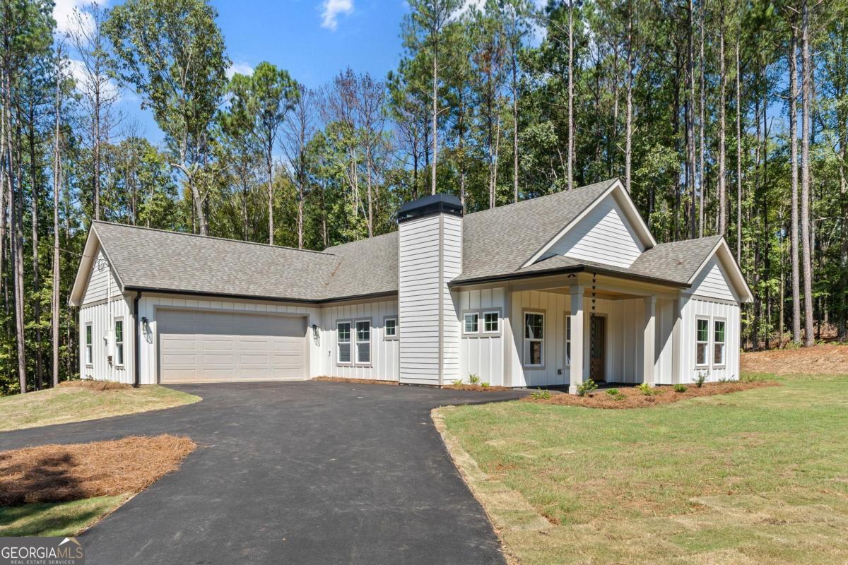 New Construction Near Lake Sinclair! Just minutes from the Twin Bridges boat ramp and docks, this craftsman-style home sits on a private 2.02-acre wooded lot and is filled with thoughtful custom touches. Inside you'll find LVP flooring throughout, upgraded trim, and spacious bedrooms with custom closets. The kitchen showcases quartz countertops, a detailed tile backsplash, pot filler, bottle washer, and abundant drawer storage, along with a walk-in pantry that also hosts the laundry. A mudroom drop zone adds everyday convenience. The primary suite impresses with a shiplap accent wall and a spa-style bath boasting dual vanities, a seamless glass walk-in shower and custom large panel tiled shower. Additional highlights include hardy board siding, custom lighting, stamped concrete covered porches on the front and back, and a two-car garage. This custom home blends quality, comfort, and location for the perfect Lake Country retreat!