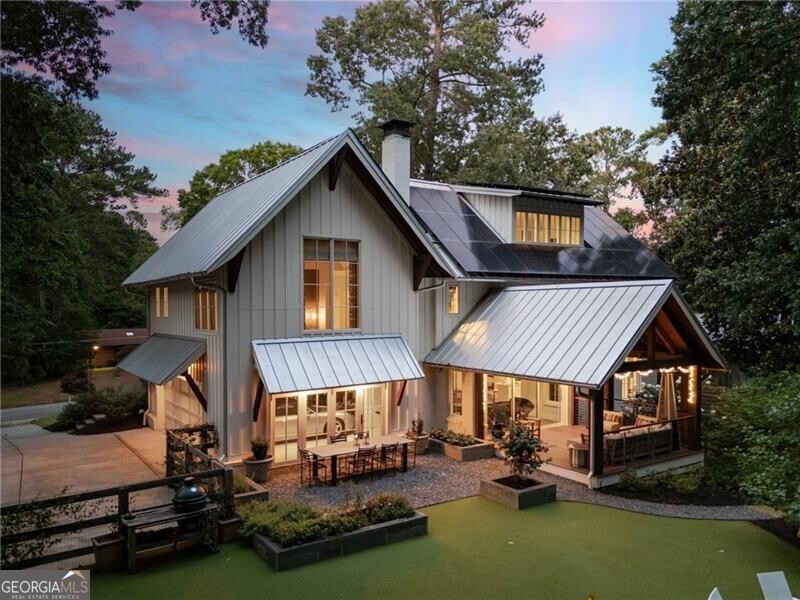 Atlanta Home Magazine's 2024 Gold Medal Award Winner, this exceptional Napa-inspired modern farmhouse in Sandy Springs offers a rare blend of architectural sophistication, high-performance living, and timeless craftsmanship. A stunning Jones Pierce design/build masterpiece set on a private, maturely landscaped half-acre lot, the fully remodeled residence spans 4,445 square feet with 5 bedrooms and 4.5 bathrooms-expertly curated for both luxury and comfort. At the heart of the home is a chef's kitchen featuring Carrera marble countertops, a farmhouse sink, new Wolf gas range cooktop, paneled refrigerator, and dual convection ovens. Just beyond, a custom butler's pantry includes built-in bar, custom cabinetry, shelving, and a wine fridge-perfect for entertaining. The adjacent formal dining room, with its generous bay window overlooking the lush front yard, sets the stage for memorable gatherings. Additionally on the main level, the bright and airy den features a reclaimed barn wood accent wall and large flat-screen TV, flooded with natural light from an oversized panoramic picture window. The living room impresses with designer lighting, a custom bookshelf, and an inviting wood-burning fireplace. Sliding three-panel glass doors open seamlessly to a resort-style outdoor patio, ideal for al fresco dining and relaxing. Upstairs, the luxurious primary suite boasts vaulted ceilings, a custom oak accent wall, gas fireplace, electric blinds, and two fully built-out walk-in closets with designer lighting. The spa-like primary bath offers dual vanities, an oversized glass shower with multiple showerheads including a rain feature, and a private water closet. Two additional bedrooms are connected by a stunning bathroom with floating mirror, dual showerheads, river stone flooring, built-in bench, and a private water closet. A beautiful fourth ensuite bedroom completes the second floor. Tucked away on the top floor, this bright and airy flex space functions beautifully as a media room, home office, or gym, featuring custom built-ins, hardwood floors, and ample natural light for a relaxed yet refined ambiance. This level also includes a full bedroom and bathroom, offering a private suite ideal for guests or extended family. The basement level includes two climate-controlled rooms currently set up with a pool table with bar, media space and play room, ideal for casual gatherings or future customization. Step outside to the 250+ square foot covered patio overlooking an Italian-inspired outdoor dining area with bluestone planters and full audio-easily controlled from your phone. The PGA Tour-grade putting green, flanked by a gas fire pit and seating area, provides a unique and immersive experience. The fully fenced backyard is enhanced by professionally landscaped walkways, stairs, and planting areas. The front of the home sits gracefully above street level with sloping Zoysia grass and native trees and shrubs, all supported by an automatic irrigation and mosquito repellent system for year-round enjoyment. Every detail of this home has been thoughtfully elevated-from solid oak and metal stairwells to custom cabinetry, crown moldings, and hardwood flooring. Smart home features include Clare full-home automation, five exterior cameras, integrated AV systems, whole-home audio, and tri-zone Trane HVAC. Environmentally conscious features include a 16kW, 38-panel solar array and numerous energy-efficient upgrades throughout. This one-of-a-kind home is an extraordinary opportunity. Schedule your private showing-homes of this caliber are rare, and this one won't last!