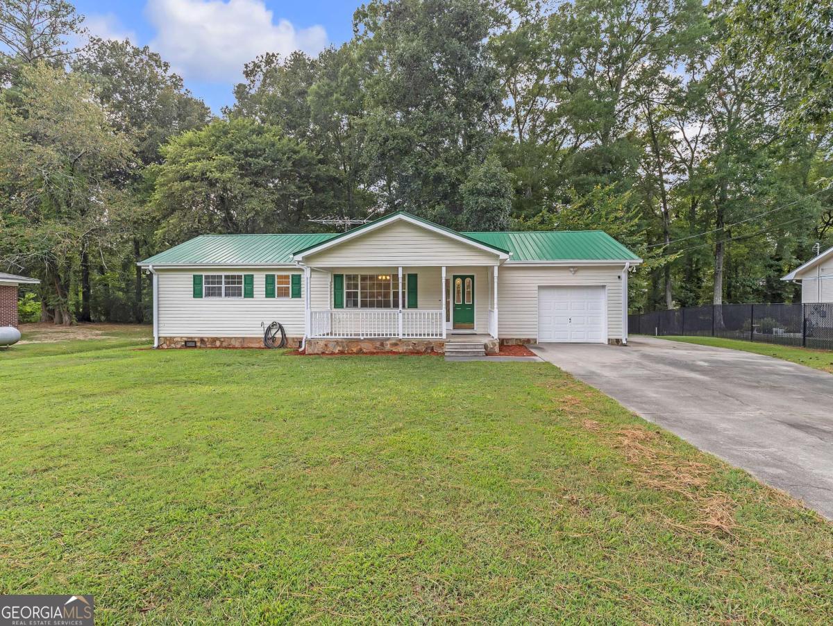 This beautifully updated 3-bedroom, 1.5-bath ranch combines modern updates with timeless charm. Freshly painted inside and out, the home features all new LVP flooring throughout and a bright, open living area, accented by a stylish chair rail detail and filled with natural light. The kitchen offers abundant cabinet space, sleek quartz countertops, and appliances, while the dining area flows seamlessly for everyday living and entertaining. The primary suite and secondary bedrooms provide comfort with fresh finishes, and both bathrooms have been updated with modern fixtures, including a tub-shower combo and refreshed vanities. A new water heater adds peace of mind. Outside, enjoy a large level lot with mature trees, a scenic wet weather creek/ditch at the back of the property, and plenty of room for outdoor activities. The inviting covered front porch, durable and freshly painted metal roof, single-car garage with a separate storage room and extended driveway add to the appeal of this move-in ready home.