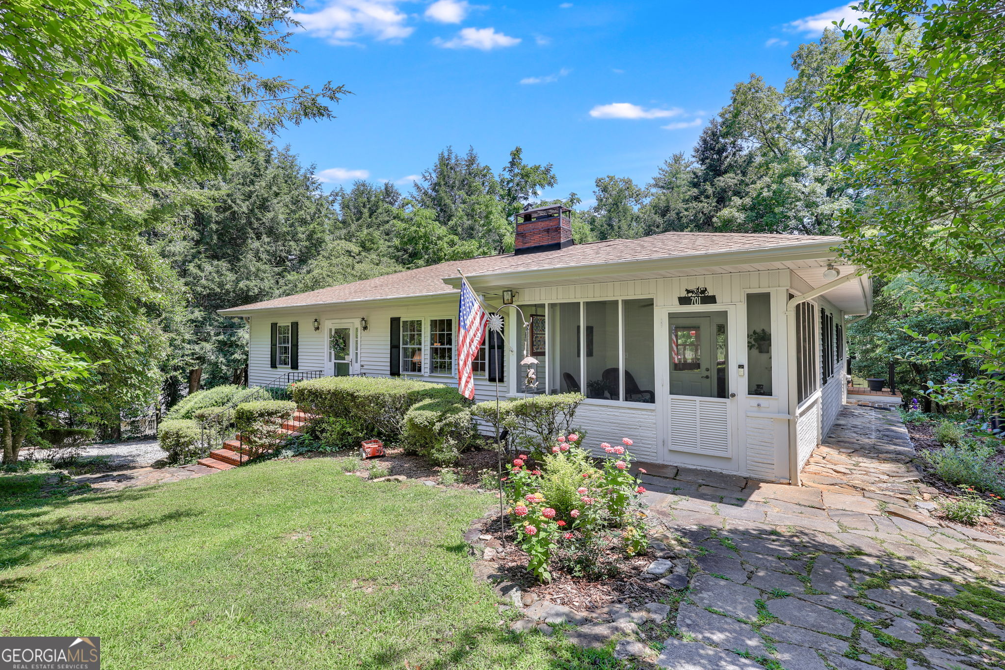 This beautifully updated 3B, 2BA home is tucked into a lush, wooded setting just a short stroll from the heart of downtown Clarkesville. With the vibrant town square just minutes away, you'll love everything about this peaceful retreat with unbeatable walkability. Step onto the classic flagstone path and you're greeted by a cheerful porch perfect for morning coffee or evening conversations. The immaculately landscaped yard bursts with color-blooming flowers, manicured shrubs, and mature trees offer privacy and natural beauty, completing the picture of timeless Southern charm. The open kitchen is a true showstopper, featuring quartz countertops and a generous center island. Crisp white cabinetry paired with stainless steel appliances, a wall of windows flooding the space with natural light, make this cozy breakfast nook overlooking the peaceful backyard the perfect place to start and end your days. 3 Gas Fireplaces, Hardwood floors, plantation shutters, and custom accents throughout reflect tasteful upgrades. The home flows effortlessly with its split-bedroom layout, updated baths, and is ideal for both relaxing and entertaining.