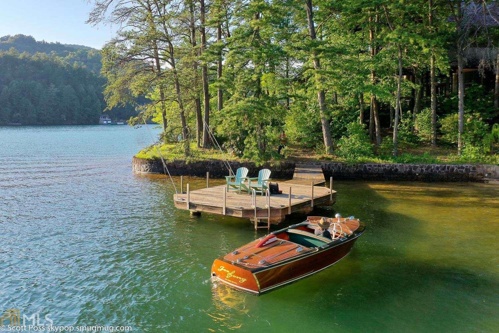 Lake Rabun - fee simple - private land - 455 feet of lake frontage - the premier location known to many as "Looker's Beach". A 1.12 acre peninsula with private beach and panoramic views of the lake and surrounding mountains. Take one step inside and the wow factor hits. It's a home of incredible design, detail and craftsmanship molded perfectly to this site. The great room fireplace, roof structure, ceiling height, beams, lighting, windows and flooring are impressive indeed as well as lake views and porches all around with a direct, covered, no step connection to the upper deck of the two stall boathouse. The living, dining and kitchen make up the center of the home and these areas flow together brilliantly. Wings extend from the great room following the shoreline. The north wing has the master bedroom suite with bath as well as a study/flex room with full bath. The south wing has 2 bedrooms and one bath. Shown by appointment. Please see the virtual tour.