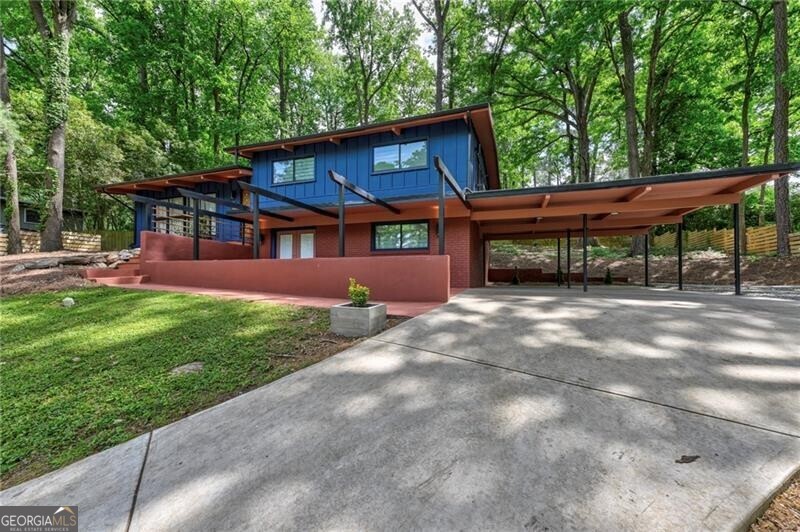 Stunning Mid-Century Modern retreat tucked away in sought-after Northcrest. Thoughtfully refreshed with meticulous detail including new furnace, driveway,  sewer line and insulated low-E vinyl windows. Private sloped approach opens to a serene, level fenced backyard, an outdoor sanctuary with mature hardwoods, lush canopy and multiple entertaining spaces including a trellis-covered patio. Inviting front porch with multiple seating zones and pergola accents sets the tone. Step through handcrafted stairs and custom Mid-Century entry to soaring vaulted ceilings with exposed, stained beams and solid-surface flooring. Light-filled family room with exposed brick feature wall and breakfast bar flows into the updated kitchen w/ white cabinetry, stainless appliances, apron-front sink, designer vent hood and breakfast nook with sliding glass doors to the backyard. Split-level layout offers three vaulted-ceiling bedrooms up, including thoughtfully redesigned shared suite-style bath configuration blending style and practicality. Finished lower level offers a second living space with brick fireplace, bar with sink, walk-out access to front patio, full bath and 4th bedroom with great natural light. Two-car carport + additional parking pad. Exceptional privacy yet moments to I-85, shopping, dining and top-rated schools. A rare, true Mid-Century gem.