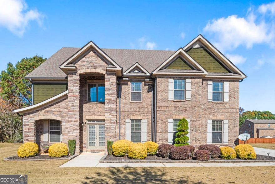 Step inside The Gem of East Lake Estates, a luxurious full-brick executive residence offering over 5,400 square feet of thoughtfully designed space across three expansive levels. Located in one of McDonough's most desirable neighborhoods and zoned for top-performing Union Grove schools, this home seamlessly blends elegance, functionality, and multi-generational living.        The main level features a beautiful formal dining room with coffered ceiling, a cozy family room with a stack stone fireplace, and a chef's kitchen with double ovens, ample counter space, and a sunlit eat-in area. A butler's pantry connects the kitchen and dining space, adding flow and convenience for entertaining.     Across from the dining room, a main-level guest suite provides private accommodations for in-laws or guests and is paired with a full ADA-accessible bathroom, offering both comfort and accessibility.        Upstairs, the oversized primary suite is a true retreat with a spacious sitting area and a spa-inspired bath with dual walk-in closets. Three additional bedrooms and two full bathrooms complete the second floor.        On the third level, you'll find a separate living space with two additional bedrooms, a full bathroom, and its own lounge-ideal for teens, extended family, or a live-in nanny.        Step outside to enjoy professionally landscaped grounds, a side-entry two-car garage, and a newly enclosed rear patio-perfect for entertaining or relaxing year-round.