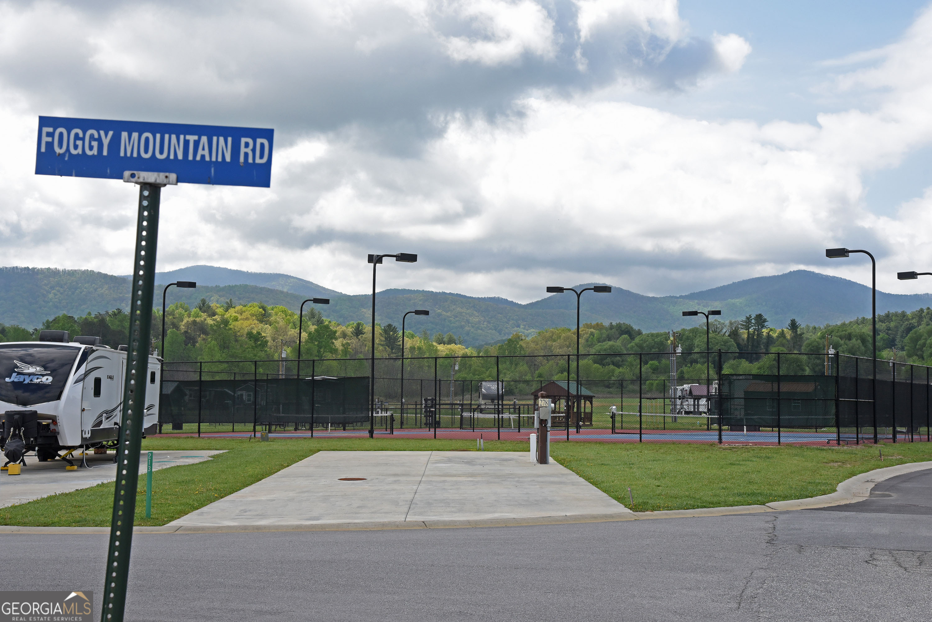 Welcome to your spacious RV lot nestled in a serene countryside setting, offering breathtaking mountain views that define the charm of North Georgia. This ultimate 5-star luxury RV park and spa is the ideal canvas for your RV or the perfect spot to create your "home away from home" tiny retreat. This corner parcel not only provides ample space for your family, including your four-legged friends to run and play, but also features added green space for extra enjoyment. With complete hookups for water, electricity, and sewage, you can relax and immerse yourself in the beauty of the landscape. If you're looking to share this space, our management team can handle everything for you through our Short-Term Rental (STR) program. Experience a lifestyle filled with relaxation and recreation in our vibrant community. Enjoy sparkling pools, a fully equipped fitness center, tennis and pickleball courts, a dog park, spa, indoor sauna, and more. The quarterly fees cover yard maintenance, Wi-Fi, garbage drop-off, and water services, making your life hassle-free. Outside the community, explore the stunning North Georgia area, from Blairsville to Blue Ridge and Hiawassee to Murphy, NC. Engage in hiking, biking, kayaking, tubing, shopping, and more. After your adventures, return home to unwind with massage chairs and a steam shower, ready to do it all over again the next day. Come where memories are made and tranquility reigns supreme!