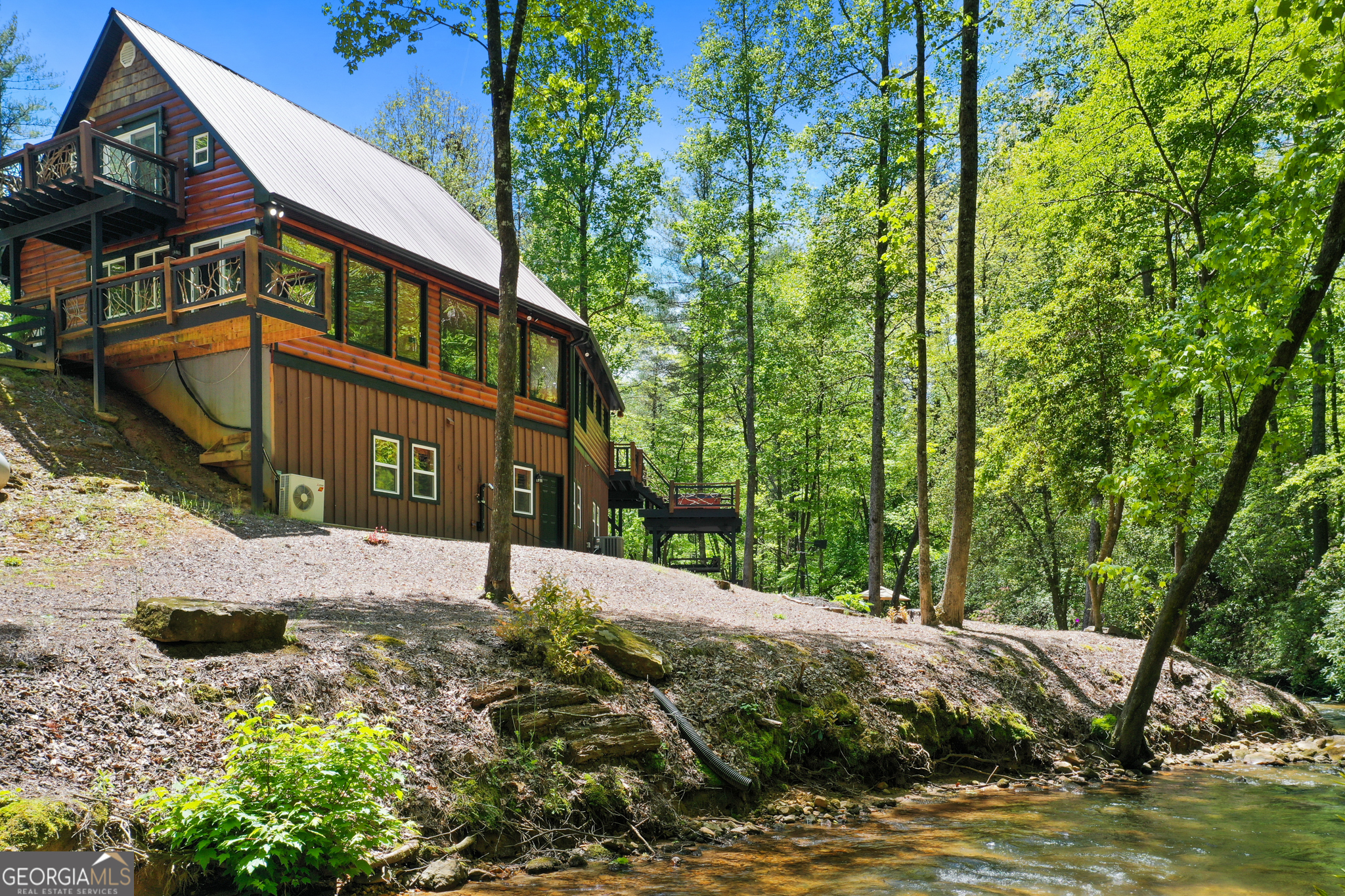Incredible year-round trout stream cabin with approximately 495+/- feet of creek frontage. This rare property offers level, wide, rushing trout waters and even your own private waterfall. Perfect as a short-term rental investment or a private mountain retreat. The craftsman-style cabin is well maintained with lots of composite decking, covered porches, fire pit, and a hot tub overlooking the stream. Inside you'll find a chef's kitchen with granite countertops, stainless steel appliances, and a spacious master suite with walk-in closets. The finished walk-out basement features a man cave, game room, or bonus room, laundry room, half bath, and a large garage ideal for your car, ATV, or outdoor gear. Located on easy, paved roads with no steep climbs and surrounded by peace and serenity in the heart of the North Georgia Mountains. Convenient to Ellijay and the Cohutta Management Area for hiking, hunting, and horseback riding. A truly rare find offering a unique blend of natural beauty and modern comfort.