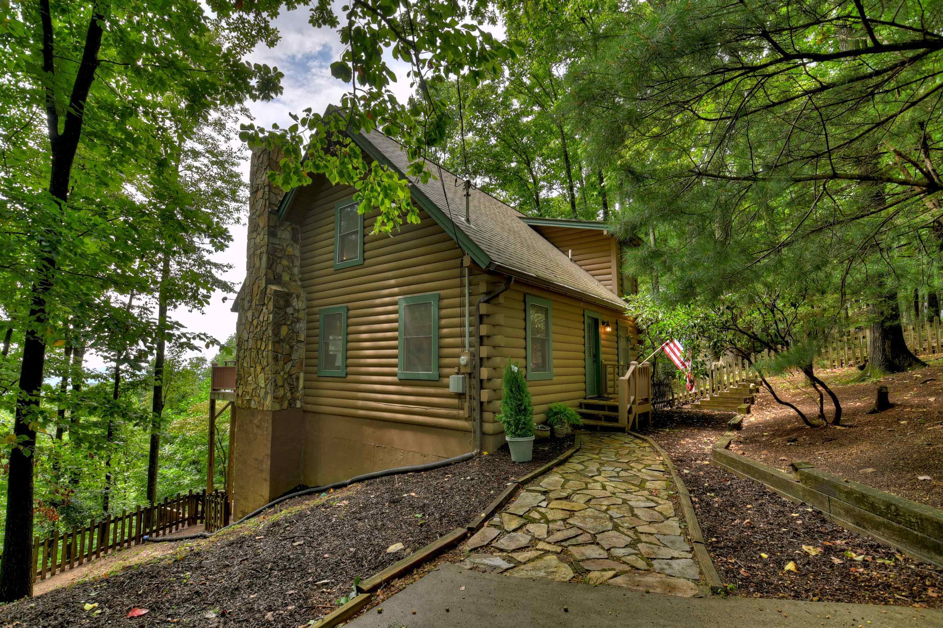 Discover your dream retreat in this beautifully renovated log cabin situated on 1+ acres along the back ridge of Walnut Mountain. This home is exquisitely furnished w/ high-end decor and boasts breathtaking year round long range views. This authentic log cabin showcases a main-level bedroom with charming beamed ceilings. The living room features a genuine wood-burning fireplace, perfect for cozy evenings. Rustic wood beams enhance the decor, while an open dining area creates a spacious atmosphere. Upgraded kitchen with brand-new stainless steel appliances, fresh subway tile backsplash, and modern butcher block countertops. Upstairs you will find an over-sized bedroom with a comfortable sitting area and a renovated bathroom featuring new subway tile, tile flooring, oil-rubbed bronze faucets, and touch-controlled vanity mirrors. An expansive walk-in closet caters to all your storage needs. A full daylight unfinished basement offers endless possibilities. Enjoy the mesmerizing views throughout the year from the ample screened-in porch and deck. This home includes access to all the amenities of this gated community including a splendid pool, clubhouse, tennis courts, lake area, and scenic hiking trails-all within a convenient 5-miles to downtown Ellijay. You or your guests can start enjoying this cabin right away as it's being sold furnished and short term rentals are allowed in this wonderful mountain community!