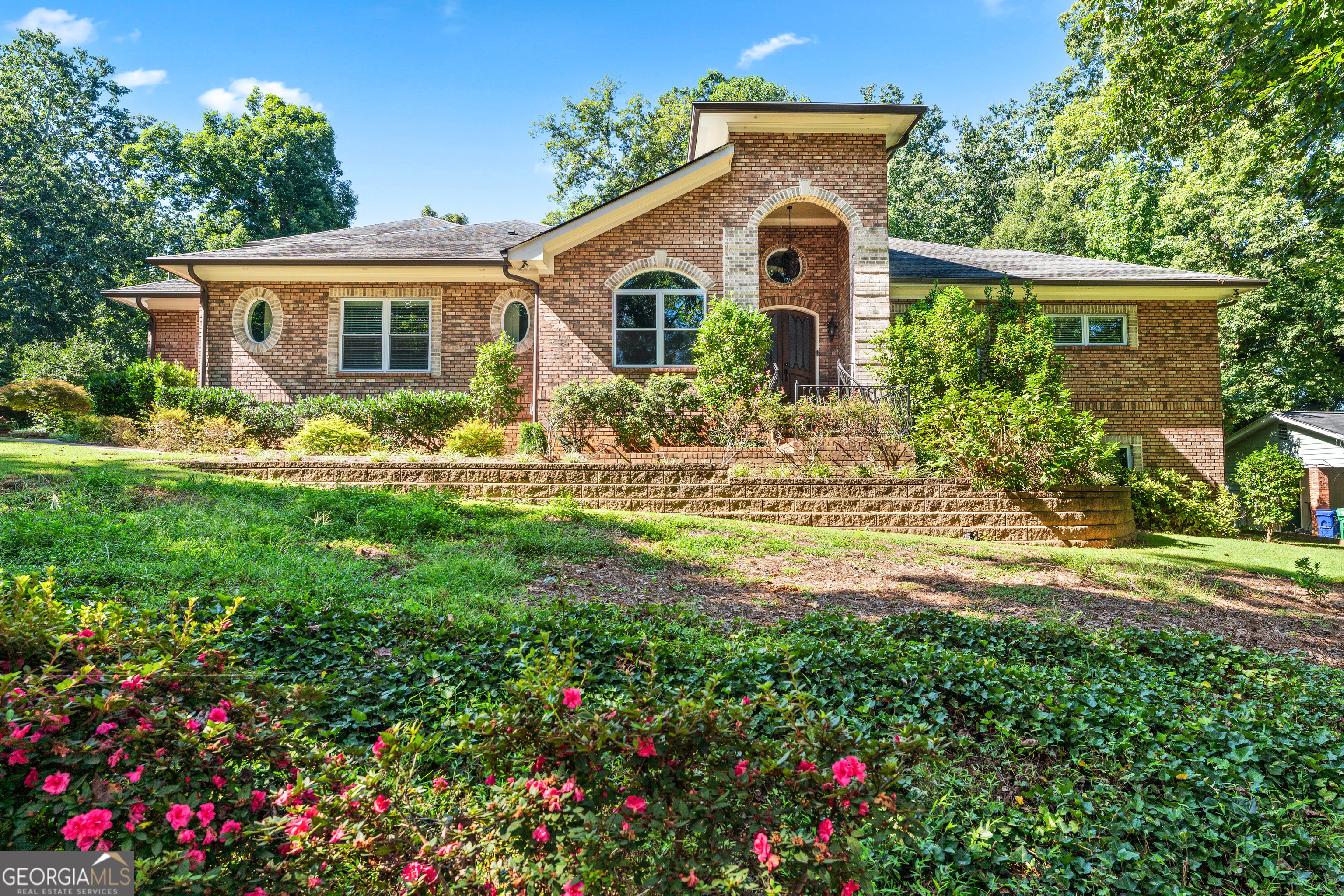 Welcome to a truly exceptional residence where luxury meets tranquility, nestled on a sprawling half-acre corner lot in a prime Dunwoody neighborhood. This custom-built home, established in 2012, offers a serene escape where you can connect with nature, often spotting deer and other wildlife right outside your window. Designed for those who love to gather and entertain, this home is a dream come true. The heart of the home features two incredible full gourmet kitchens, offering both gas and electric cooking and an abundance of storage for all your culinary needs. The open-concept design flows seamlessly from the grand entrance, with its magnificent custom doors, into a spectacular great room with a cozy fireplace. The separate dining area, ready to host over a dozen guests, promises unforgettable dinner parties and holiday feasts. The main level lives beautifully with a lavish primary ensuite featuring a custom closet, a spa bath with steam shower and heated floors, and a private lanai for quiet moments. Two additional secondary bedrooms on the main offer easy one-level living for family or guests. A beautiful office elevates work and creativity with a full wall of rich dark-wood built-ins and a charming chandelier. Upstairs, a second primary suite with its own full bath creates a perfect haven for in-laws, teens, or long-term visitors. Step outside onto the covered deck to enjoy the beautifully landscaped private yard. The full unfinished basement, already stubbed for a bathroom, offers a blank canvas for you to create a personalized space-whether it's a home theater, a gym, or an additional living area. With no HOA restrictions, you have the freedom to enjoy your property as you wish. The location is truly unbeatable-a peaceful retreat with easy access to everything. You're just a short walk from the top-rated Austin Elementary School and in the highly sought-after Peachtree Charter Middle and Dunwoody High School district. Spend your weekends exploring the Dunwoody Nature Center, playing a round at the Dunwoody Country Club, or simply walking to downtown Dunwoody to enjoy its charming restaurants and shops. This is more than just a home; it's a lifestyle waiting for you to embrace.