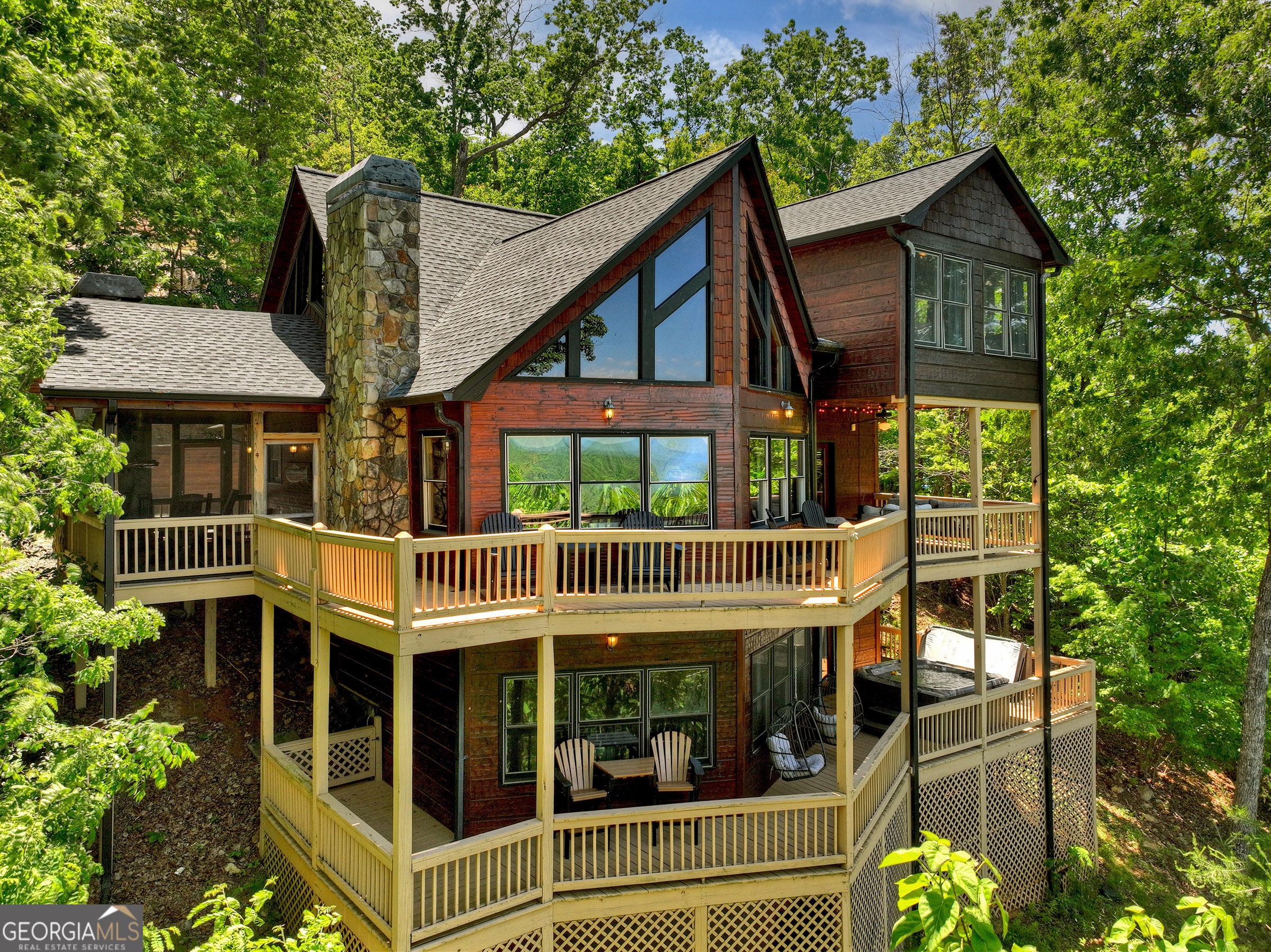 Discover lodge style living in this stunning prow front chalet overlooking some of best views in North Georgia! With close proximity to some of the area's best hiking and biking trails, the Toccoa River, and Lake Blue Ridge, this retreat is the perfect spot for the mountaineer at heart. Complete with three levels of living with outdoor spaces that rival the sprawling interior, soaring cathedral ceilings, warm wooden accents, stone fireplace, gourmet kitchen, slate showers, and stone countertops. Primary suite has a private balcony, in-suite fireplace, and lush mountain views. Lofted area has an additional bunk room or would be the perfect study. Terrace level is complete with a large den, game room, and party porch with jacuzzi. Other special features include a brand-new roof, double carport, and sold fully furnished!