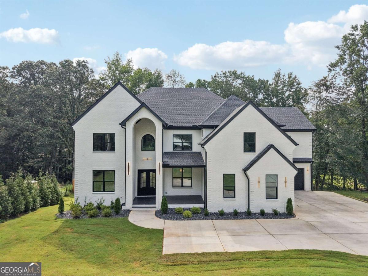 *Buford City Schools MEET New Construction with NO HOA, 4 car garage and terrace level! This remarkable estate is a true testament to architectural grace and refined living, offering the perfect balance of grandeur and comfort. Wrapped in four-sided brick and surrounded by lush professional landscaping, the home presents timeless curb appeal on nearly three-quarters of an acre in one of Buford's most coveted settings. From the moment you step through the dramatic double doors, the two-story foyer greets you with soaring ceilings and a breathtaking chandelier that sets the stage for the elegance that unfolds throughout the residence. The living room serves as the heart of the home, crowned with coffered ceilings and framed by windows that bathe the space in natural light. A striking fireplace with custom built-ins and a bold accent wall creates a dramatic focal point, while designer lighting enhances the atmosphere both day and night. Just beyond, a well-appointed wet bar along the back wall-conveniently located by the breakfast area-offers the perfect touch for entertaining, whether serving morning coffee or evening cocktails. For the culinary enthusiast, the kitchen is a showpiece of design and function. Anchored by an oversized waterfall quartz island with deep sink, it boasts custom white cabinetry with glass-front displays, elegant stone counters, and cabinet lighting that adds both warmth and sophistication. A professional-grade JennAir six-burner gas range with pot filler is complemented by a suite of stainless appliances, while a secondary walk-in kitchen with its own Frigidaire five-burner gas cooktop, sink, and extensive cabinetry ensures seamless preparation and effortless entertaining. A spacious walk-in pantry completes the chef's domain. The main-level primary suite is a private sanctuary, offering both comfort and indulgence. A fireplace anchors the room, while oversized windows frame views of the grounds. The spa-inspired ensuite bath is designed to rejuvenate, featuring a freestanding soaking tub, an oversized frameless dual-head shower, dual vanities with makeup space, and touch-screen mirrors with adjustable lighting. A custom walk-in closet with built-in shelving and a center island transforms daily routines into a boutique dressing experience. Upstairs, four generously sized bedrooms each feature their own ensuite bath and walk-in closet, providing privacy and comfort for family or guests. A media lounge with fireplace and built-in bar invites relaxed evenings and lively gatherings, while a dedicated office with custom shelving and large windows creates a light-filled space for productivity. The expansive unfinished terrace level offers nearly 3,000 square feet of possibilities with exterior access, providing the perfect opportunity to design a private retreat, home theater, gym, or entertainment hub tailored to your lifestyle. Outdoors, the home continues to impress with a fully fenced backyard designed for privacy and enjoyment. Professional landscaping, outdoor lighting, and an irrigation system frame a built-in grill station and spacious patio, creating the ideal setting for al fresco dining, entertaining, or quiet relaxation. Additional highlights include dual laundry rooms, a mudroom with built-in storage, and over 1,000 square feet of garage space for multiple vehicles and storage. Every detail was thoughtfully curated to elevate convenience while showcasing refined craftsmanship. Perfectly positioned near Lake Lanier, the Mall of Georgia, and premier dining and entertainment, this residence offers the best of Gwinnett living. Families will appreciate the award-winning Buford City Schools, while professionals benefit from easy access to I-85 and I-985 for seamless connectivity. This is more than a home-it is an estate of distinction, where timeless architecture meets modern luxury, crafted for those who demand only the finest.