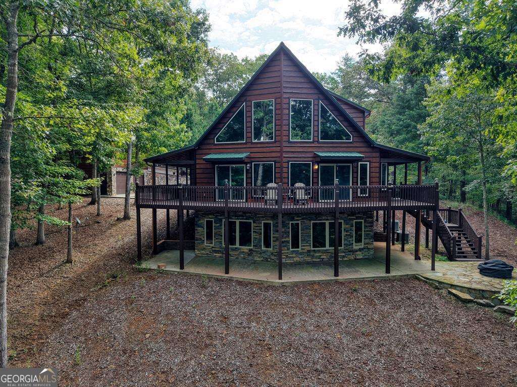 Beautifully maintained rustic-style home nestled on 4.5+ private, usable acres in a quiet neighborhood of quality homes, just minutes from the north end of Lake Nottely. Inside, you'll find a warm all-wood interior with unique custom finishes, granite countertops, stone fireplace, custom window treatments, and soaring cathedral ceilings in the open main living area. The main level offers a spacious kitchen, large primary suite, and convenient half bath. Upstairs features an open loft and a second ensuite, while the terrace level includes a versatile game room/man cave, additional bedroom, and full bath. Outdoors, enjoy a wraparound porch and deck overlooking gentle, walkable land with open pasture and a bold, rushing creek along the property line. Easy paved access and convenient location to Blairsville, Blue Ridge, and Murphy, NC.