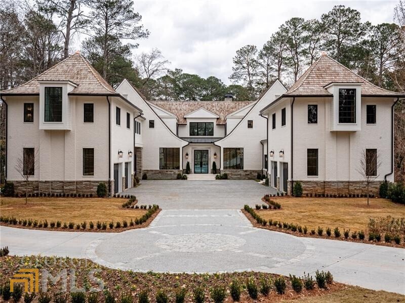 Tucked away on one of the most sought-after streets in the heart of Buckhead, an exquisite collaboration between Harrison Design and White Oak Fine Homes produced this inspired transitional style home completed in Dec. 2021. From the impressive steel front entry doors to the extensive use of natural stone elements, Venetian plaster and other bespoke touches, it's apparent that no detail was overlooked in crafting this one-of-a-kind tour de force of design executed by the O'Donnell Group. An open and inviting layout features soaring arched ceilings and a large expanse of windows positioned to bathe the space with natural light and provide breathtaking views of the pool and manicured grounds. Envisioned to accommodate everything from the flow of daily life to entertaining on a grand scale, the show-stopping kitchen is anchored by a dramatic 11' waterfall edge island enrobed with Calacatta marble extending to the countertops and backsplash behind the Wolf range and custom designed range hood. From the kitchen, the floorplan opens to a sunny breakfast room and dramatic living room anchored by a massive 48" fireplace with custom limestone mantle and hearth. The main level primary bedroom suite features a dramatic vaulted ceiling, arched windows, large natural stone fireplace and private access to the pool and gardens. Custom designed dual closets and an elaborate bath with heated Blavet Blanc limestone floors, floor-to-ceiling Amalfi satin tile, a glass surround walk-in shower with dual shower heads, separate oversized soaking tub and custom cabinetry complete this opulent owner's retreat. Additional enviable features include a spectacular wet bar and wine cellar cabinet with space for 300 bottles, a virtual learning room, finished daylight terrace level, and an additional upper-level guest suite with private entrance.