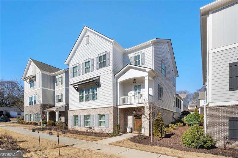 PRIME LOCATION! This exquisite, nearly new custom-built home is nestled in the highly desirable Manget community. Just moments to the Marietta Square, offering vibrant restaurants, breweries, shopping, entertainment and more, giving you a warm community feel. It is also close to several parks, the hiking trails of scenic Kennesaw Mountain and with easy access to I75 and I575! This three-story Tristan floorplan by Traton Homes is a modern gem with 10 ft ceilings, plenty of natural light and over $50,000 in builder upgrades and high-end finishes including: hardwood floors throughout, plantation shutters on every level and designer hardware and fixtures. When you enter from the screened-in porch, perfect for enjoying some outside time and visiting with neighbors, you are welcomed into the main living area. This includes an open-concept chefs' kitchen with quartz countertops, stainless steel appliances including a double oven, built-in microwave, five burner gas stove, dishwasher, oversized sink and plenty of cabinet storage. The dining room and family room, with painted brick gas fireplace and built-in cabinets can also be found on the main level. Up the stairs, on the third level, you'll find an open landing with storage closets just outside the primary bedroom. The owner's suite is a sanctuary with soaring ceilings, abundant light and ample space for a cozy sitting area. And the primary bath is just as spacious with double vanity, private water closet, spa-like oversized ceramic tile shower with a bench seat. You'll also find a large walk-thru closet, big enough to be considered a dressing room. Two secondary bedrooms, another full bath and the laundry room complete with utility sink round out the third level. The terrace level has its own covered brick front porch entrance, adjacent to the courtyard fire pit area, and brings you into a sitting room, 4th bedroom, spacious media room and a full bath. This home has as many great features inside as outside with two car garage, professionally landscaped lot, Kirby park around the corner where you can play Bocce Ball and is surrounded by open spaces and pet-friendly areas to enjoy the sunshine with friends and family.
