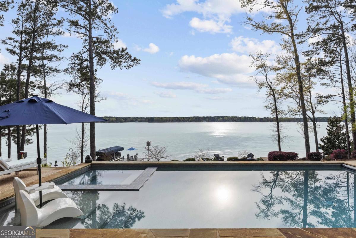 Exquisite luxury lake home in Reynolds Lake Oconee crafted by DreamBuilt and Black Sheep Interiors with unparalleled sunset views over the expansive lake. Kingfisher Point in The Landing is where the enchantment of Sunset Views meets Lake Oconee's beauty. This lakefront residence exemplifies the pinnacle of luxury and comfort with three bedrooms plus a bonus bedroom and future apartment above the 3-car garage. The great room boasts vaulted ceiling and framing breathtaking views of the lake and the ever-changing sunset canvas, complemented by top-tier built-ins, masonry fireplace for an ambiance of refined sophistication. The home's design seamlessly connects this space with the custom-designed dining area and the gourmet kitchen, creating an open, functional floor plan ideal for lakeside living.The kitchen, a masterpiece of design and utility, features carefully selected finishes and is equipped with premium appliances, Subzero and Wolf, setting the stage for culinary excellence.Adjacent to the kitchen, the butler's pantry and wine room with a second full refrigerator, offer discreet functionality, perfect for meal preparation and storage. One of the home's crowning jewels is the expansive screened porch, complete with a fireplace featuring unobstructed views of Lake Oconee and sunset. A fantastic grilling deck designed to enjoy the view is adjacent to the porch. There is an office and spacious laundry room on the way to the expansive three car garage. One of the special features of the home is the professionally designed and installed K-9 turf for your furry family members. Above the garage is a plumbed and prepped expansive space for a future guest suite or apartment. The primary suite on the main level serves as a secluded haven, offering magnificent lake views and en-suite spa-like bathroom, with heated floors, crafting a sanctuary of relaxation. Descend to the terrace level to discover the ultimate family and entertainment space with a Sony UHD projector and 110 inch screen. The custom bar features a 55 inch TV, icemaker, subzero wine cooler and Miele dishwasher. This level is complemented by a guest suite, a spacious bunk room for kids and adults and a bonus bedroom. There is an exercise room with a 3rd full size refrigerator. This level extends to a magnificent outdoor with a captivating pool and deck, set against the sunset.A lakeside firepit and private dock provides the venue to watch the show of colors every evening. Membership is available.