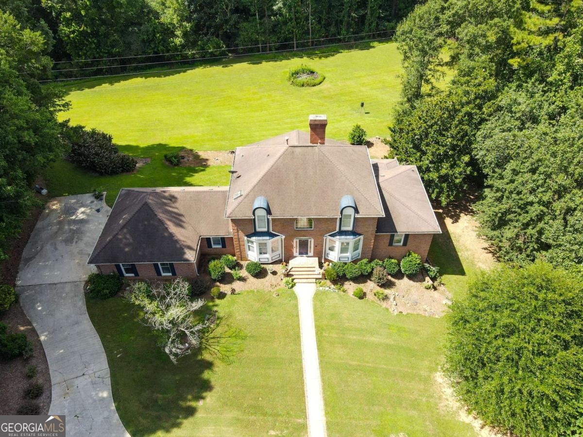 Lilburn Luxury Grand Estate on 2.43 Acres- A rare opportunity with No HOA in the Brookwood High School District! Welcome to your private retreat in the heart of Lilburn! This expansive 4BR, 3.5BA estate offers nearly 4,000 sq ft of living space-plus an unfinished basement with endless possibilities to add more square footage. Nestled on 2.43 pristine acres with a serene creek flowing just beyond the backyard, this home combines luxury, space, and tranquility like no other. Step inside the dramatic two-story foyer that opens into a spacious formal dining room that easily seats 12+, a flexible office or sitting room, and an inviting family room with fireplace. The updated kitchen is a chef's delight, complete with granite countertops and abundant cabinetry. On the main level you will find an oversized Laundry Room with incredible flexibility- previously used as a hair salon, this space offers excellent work-from-home or studio potential. Soak up the natural light in the enormous sunroom or step onto the oversized deck-perfect for relaxing or entertaining. This estate also features not one, but TWO oversized owner's suites-one on the main level and another upstairs. Upstairs also includes two additional large bedrooms and 2 full baths. The full unfinished basement is already stubbed for a bathroom and features a floor to ceiling brick fireplace, ready for your custom vision. With a 3-sided brick exterior, an oversized garage, and seller concessions for needed repairs, this home is packed with potential. Opportunities like this don't come often with acreage, luxury and room to grow!