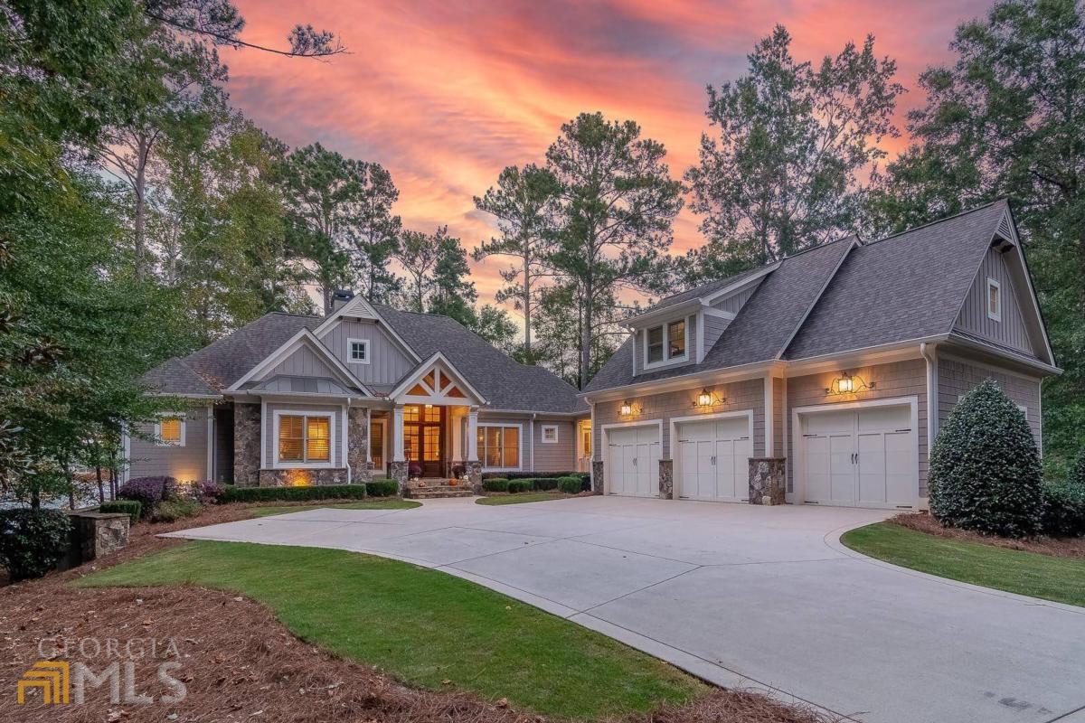 "BEAUTIFUL LAKEFRONT HOME AT REYNOLDS LAKE OCONEE WITH INCREDIBLE SUNSET VIEWS, MINUTES TO THE RITZ CARLTON AND LAKE CLUB!" Quality abounds in this lake front home featuring five bedrooms with the master and additional bedroom suite located on the main level, open floor plan with design details such as wainscoting in the living room and casual dining room (with butler's pantry), large screen porch with fireplace, chefs kitchen with island seating, large keeping room with fireplace and breakfast area, all overlooking Lake Oconee. This stunning level, deep backyard has 165 feet of water frontage and a private dock with two boat lifts. The terrace level has two en suite bedrooms, gym with sauna, family room, billiard room, wet bar with full size refrigerator, lots of storage, covered patio for outdoor dining, and firepit. Membership is available for buyer to enjoy six golf courses, tennis courts, pickleball courts, restaurants, gym facilities, pools, marinas, walking trails, and special member events of Reynolds Lake Oconee.