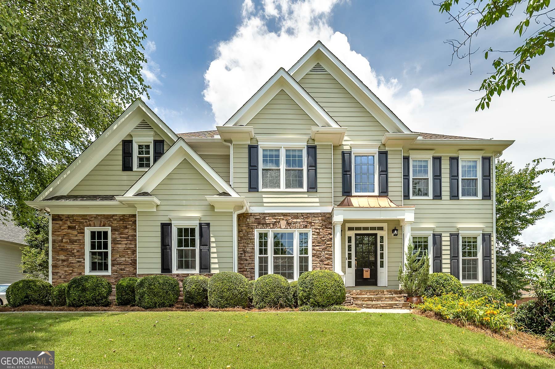 This stunning, spacious, light-filled beauty is situated on a landscaped, private lot located in Prestigious South Forsyth. This large, luxurious home was designed for family and entertaining. The fine architectural features and finishes accentuate the ideal floor plan for family and guests. Step into the 2-story light-filled foyer onto lustrous hardwood floors. To your left is a formal dining room perfect for hosting elegant dinners for 12 or more guests. To your right are picturesque French Doors opening into a home office with built-in bookcases. Directly in front of you is a sweeping two-directional staircase to the 2nd floor. Past the staircase with wrought iron banisters is the large, open family room with a stone fireplace framed by a decorative mantle. Open to the family room, the well-equipped kitchen features both a breakfast bar and nook ideal for brunches or after-school snacks and homework. Main level guest bedroom offers privacy and comfort with a spacious closet and a full bath that is conveniently located off the kitchen. Upstairs and to the right are two bedrooms with walk-in closets and a full bath. Upstairs to the left is another bedroom with a walk-in closet, a laundry room, and a huge master suite. The master suite features a huge walk-in closet. The totally renovated master bath has a double vanity, designer soaking tub with a shower wand, and a separate glass-encased shower. The partially finished basement features even more space for various interests and entertainment, including a workout room, a bedroom, and it is stubbed-out for a bathroom waiting for your finishing touches. The rear exterior of this home offers a wood deck overlooking the decadent flagstone courtyard with a massive stone fireplace and planters. Host a barbecue by the fire in this inviting outdoor space. Your family will love the area, conveniently located near Recreation, Parks, and Cultural Services, where fun and community come together. The county offers an outstanding park system, highlighted by landmarks like Fowler Park and the scenic Big Creek Greenway with walking trails, playgrounds, sports fields, arboretums, and so much more.