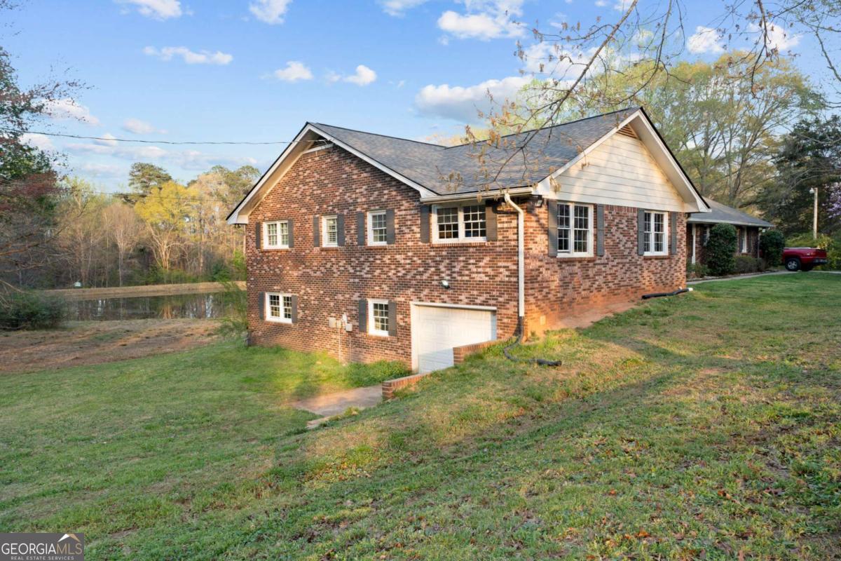 On the main level, you will find Hardwood flooring, fresh paint, and an inviting open-concept design. Wood-burning stove and an expansive covered back deck, where you can relax, entertain, and take in breathtaking views of the pond, the perfect spot for morning coffee or evening sunsets. The fully finished walk-out basement is perfect as a mother-in-law suite, guests, or rental opportunity. This includes a full bath, private bedroom, spacious living area, and stubbed for a kitchen. The boat door and workshop add even more functionality, making this the perfect home for hobbyists, car enthusiasts, and those who love extra storage! This property is a homesteaders dream! Huge chicken coup with brooding area, county water and well available, Spring-fed fishing pond, lush blueberry bushes, muscadine grapes, wild blackberries, and Pecan trees. Spacious goat pasture ideal for livestock or expanding your farmstead. And dont forget the neighbors horses playfully roaming right behind your barn, adding to the peaceful country charm. Plenty of space to roam, garden, and grow, you can truly live off the land while still being just minutes from grocery stores, coffee shops, and dining.