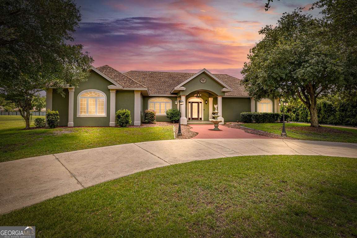 This beautifully crafted three-bedroom, two-and-a-half-bath home offers quality finishes and peaceful water views on a half-acre lot. Overlooking a scenic pond, the property combines thoughtful design with functional living. Inside, 10-foot ceilings, crown molding, and coffered details showcase the home's craftsmanship. Durable porcelain tile runs throughout the home, and a cozy den with oak accents and a fireplace adds warmth and character. The kitchen features modern appliances, plenty of cabinetry with wood shelving throughout, and a breakfast bar, opening into a dining area with backyard and pond views. The screened patio is ideal for outdoor meals or relaxing in nature. The spacious owner's suite includes patio access and a luxurious ensuite with soaking tub, shower, and dual vanities. Two additional bedrooms and a full bath offer flexibility for guests or family. Outside, enjoy mature landscaping, a private backyard, and tranquil pond views. A detached 24' x 20' garage provides extra storage or workspace, in addition to the attached garage.