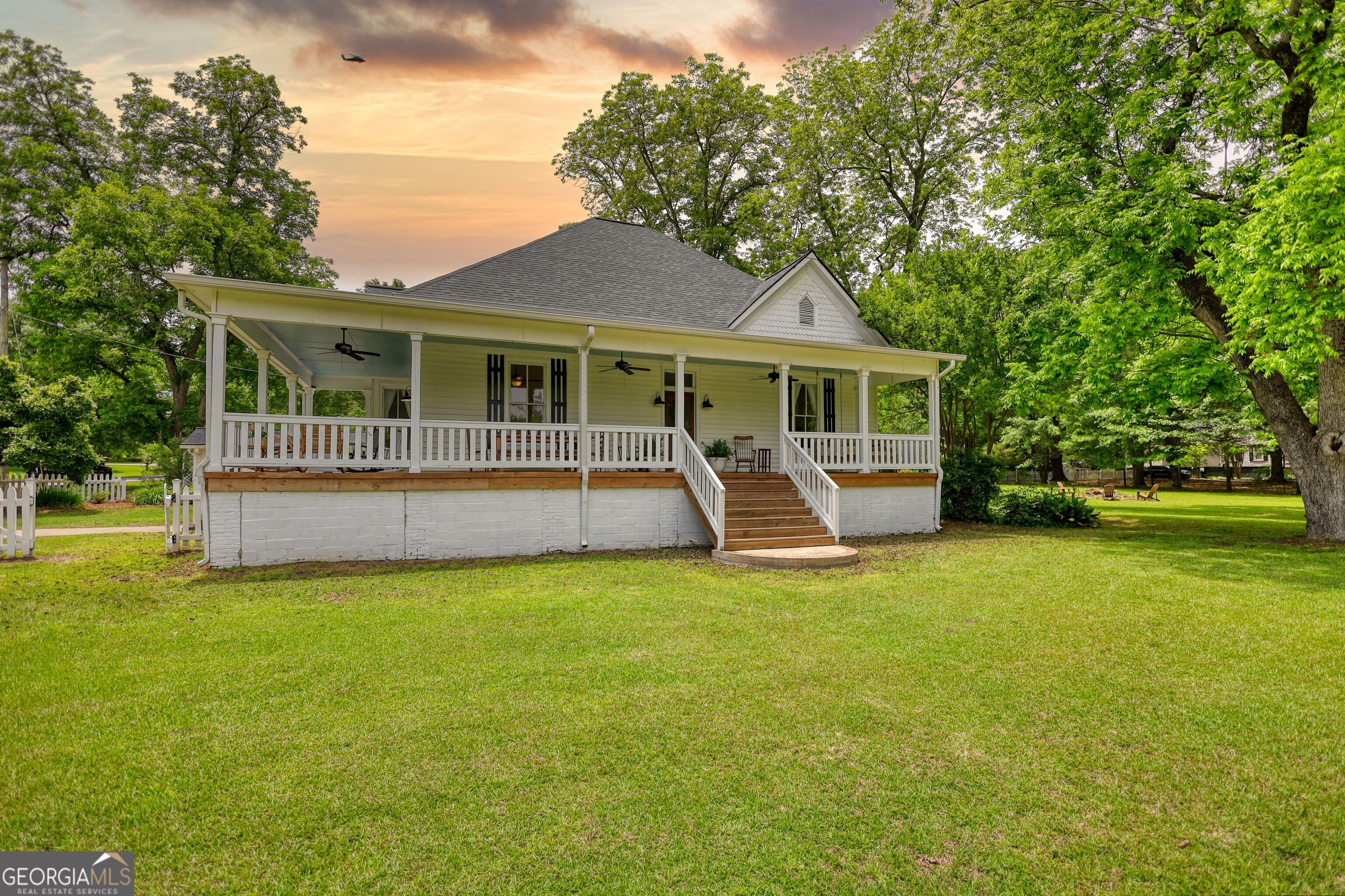 Step into the charm of 1909 with all the comforts of a modern renovation in this beautifully restored historic home, tucked away in the heart of Newborn, Georgia! A one-stoplight town full of small-town character, yet close enough to big cities for everyday convenience. Set on a spacious 1.81-acre corner lot, this property is wrapped in fencing, including a classic white picket fence out front, and surrounded by beautifully landscaped grounds that offer both privacy and charm. The wraparound front porch is a true showstopper, offering the kind of curb appeal you'd expect to see in Southern Living magazine. It's the perfect place to sip coffee, read a book, or simply enjoy a quiet evening outdoors. Inside you're greeted by original hardwood floors, soaring 12-foot ceilings, and tons of natural light. The home features two spacious bedrooms, along with a large central room that's currently used as a dining area but could easily function as an office, second living space, or whatever fits your needs. Everything feels open, airy, and thoughtfully laid out. The home was completely remodeled in 2019, including a brand-new kitchen, roof, AC unit, hot water heater, and updated systems - so while the bones are full of history, the home is fully modern where it matters. Out back you'll find mature trees, beautiful landscaping, and multiple outbuildings that add both function and personality! A she-shed, a traditional barn, a storage building, and even a storybook-style playhouse. With fencing around the entire property and high-speed fiber internet, it's ready for anything from gardening and hobbies to remote work and weekend entertaining. This home isn't just a place to live, it's a place to slow down, spread out, and truly enjoy! If you've been waiting for something special, this might just be it!
