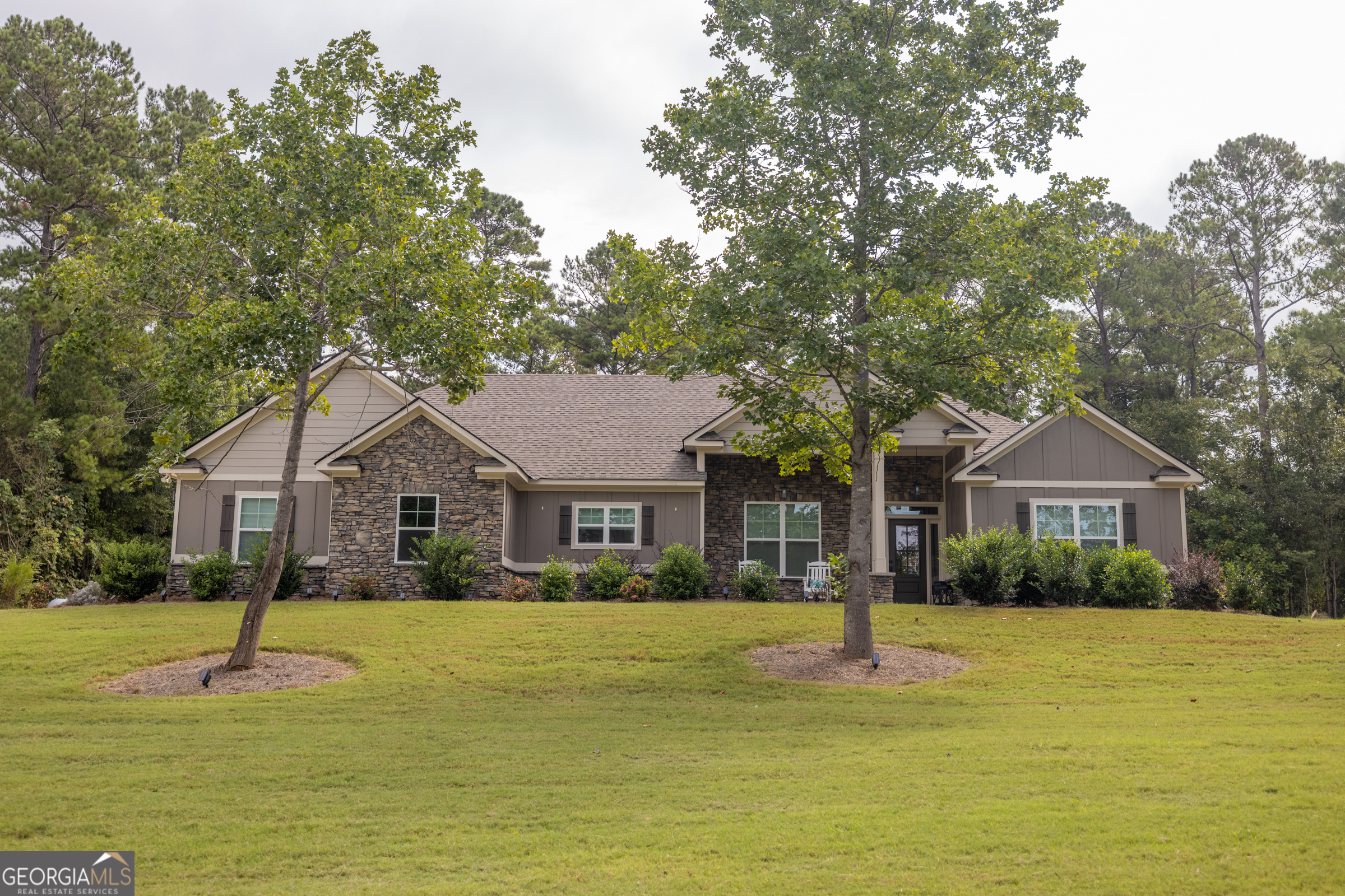 Welcome to this beautifully crafted, less-than-3-year-old home sits on a generous lot in the heart of Harris County-just 10 minutes to Harris County High School and 20 minutes to Ft. Benning. Thoughtfully designed and full of charm, this home offers a rare mix of comfort, style, and practicality. Stepping inside, you'll find custom crown molding throughout and a warm, inviting stone fireplace in the family room. The gourmet kitchen is a true showstopper, featuring modern finishes, a large kitchen island with breakfast bar, and a dedicated dining room perfect for hosting. The primary suite includes a separate tub and shower, double vanity sinks, and plenty of space to unwind. A spacious laundry room and versatile mudroom add to the home's everyday functionality. Enjoy your large open back yard with private covered patio, or take advantage of the portable building with slab and power-ideal for a workshop, storage, or home office. Plus, a brand-new gas-powered generator means you're always covered. No HOA, plenty of space to spread out, and beautifully finished from top to bottom-this one truly checks all the boxes.