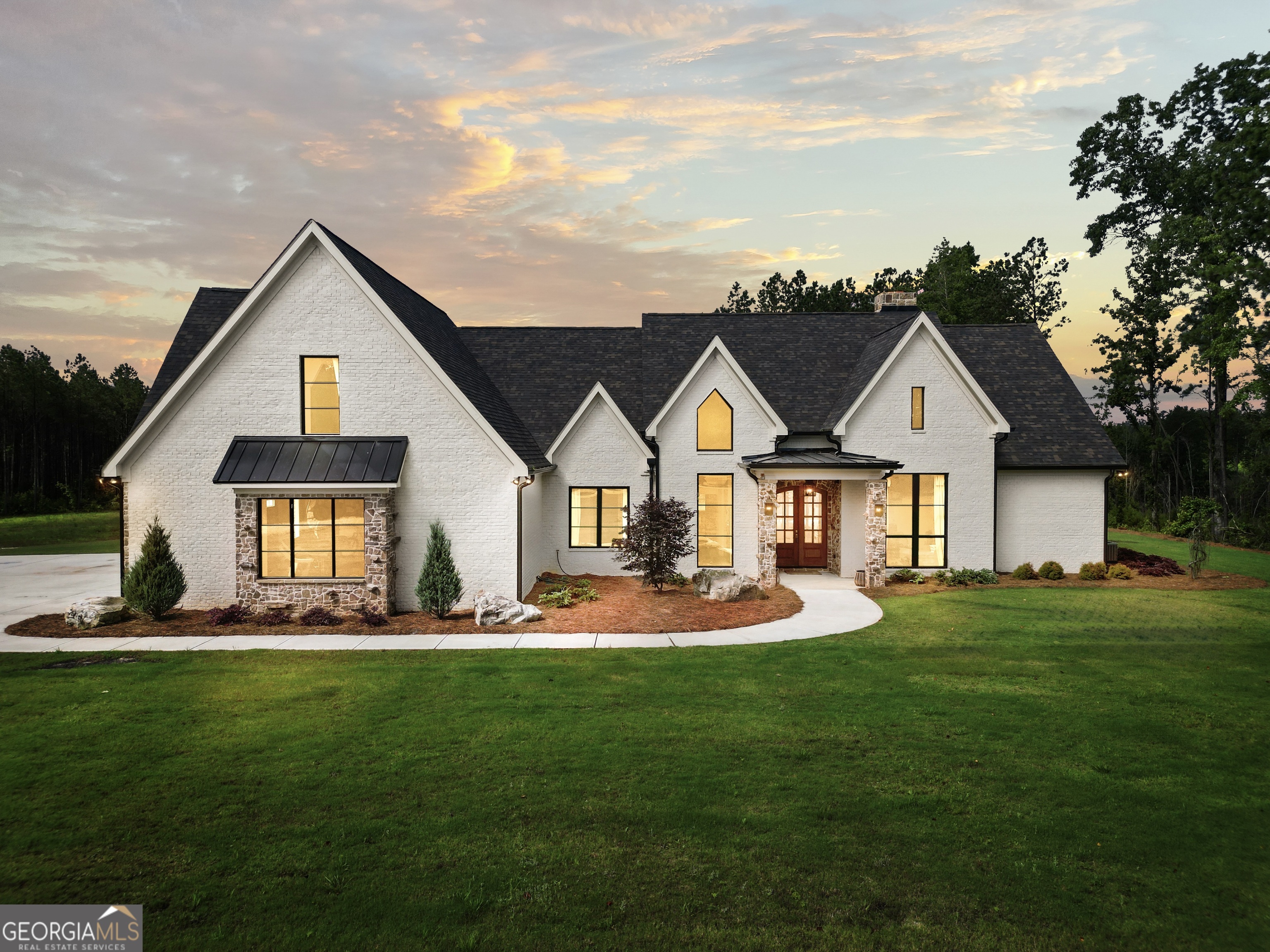 Tucked away in complete privacy, this exceptional 5,430-square-foot, 5 bedroom, 5 bathroom French Country estate captures the essence of refined countryside living in Monticello, Georgia. Set on 105 acres of gentle rolling hills and pretty woodlands this property is a rare blend of extraordinary elegance, modern comfort, and natural beauty. The home's exterior is a picturesque nod to classic French architecture, with a stone and brick facade, steeply pitched roofs, copper accents, and charming landscaping. Inside, the unparalleled craftsmanship is immediately evident- Soaring ceilings with so many exquisite details; where every hard surface has been sealed with non-toxic sealant and all interior paint is Low Voc, views of your gorgeous landscape through Quaker Quartz Luxury Windows, locally hand-hewn real Hickory floors, Travertine Matte Porcelain Tile in the laundry & bathrooms, and grand Masonry fireplaces- with impressive stonework all hand cut and designed on site create an atmosphere of warmth and exclusive sophistication. The elegant kitchen features lovely real brick floors, stunning Zia Handmade Tile backsplash, Natural Oak soft close Cabinetry, genuine Copper sink + Copper cabinet pulls from the UK. The hidden Butlers Pantry offers beautiful shelving & room for an extra fridge and freezer. Designed with both everyday comfort and entertaining in mind, the kitchen blends seamlessly with the large dining space and living room offering space for intimate family meals & cozy movie nights and entertaining a large crowd. The living room boasts a feature wall of hand cut and crafted stone with a real Hardwood Mantle surrounding the masonry fireplace. Located on its own side of the home, The Master Suite is a luxurious retreat, offering divine privacy and space. From the soaring ceilings to the giant His & Hers closets, this space is sure to make you feel comforted and affluent. The en-suite bath features beautiful Walnut-stained double doors, white Cast-Iron free-standing tub and lavish bronze fixtures, stunning Zia Handmade Tile Master Shower, and His & Hers vanities. Across the home, past the Sound-Proof Home Office, you'll find the grand hallway (also soundproof) where there are 3 more bedrooms and 2 full bathrooms with beautiful luxury wallpaper. Venture upstairs to the giant 5th bedroom/guest suite with its own brick bathroom. Past the upstairs suite there is a large bonus room with a precious reading nook ideal for a media lounge, hobby studio, or kids hangout/play space. Venture further to the upstairs Family Room featuring its own Masonry Fireplace with Herringbone details + another full bathroom. You'll also find ample attic storage space, easily accessed through stylish doors. Outside you'll find so many unique activities, your home will become the cornerstone of entertaining and sweet memories for years to come. Wander, ride or exercise on over 7 miles of manicured trails reaching every corner of the property with multiple creek crossings. Within those trails, starting in the backyard- you have a Professionally designed 18-Hole Disc Golf Course. If you fancy a workout, the garage has been transformed into a Professional gym complete with tall mirrors, fans and Olympic Grade Flooring. A unique hidden feature of this home is the Rock-Climbing Wall located on the exterior of the garage. Dine alfresco, relax or entertain on the Veranda overlooking it all. Important to note: The HVAC is zoned (3 zones), the whole home has instant hot water & top-of-the-line water filtration system on the well. The well is 600ft deep & pumps 7 gallons per minute. There is an auto controlled irrigation system in the yard. In this home, luxury is an experience all around. Do not miss this remarkable, one-of-a-kind home!!