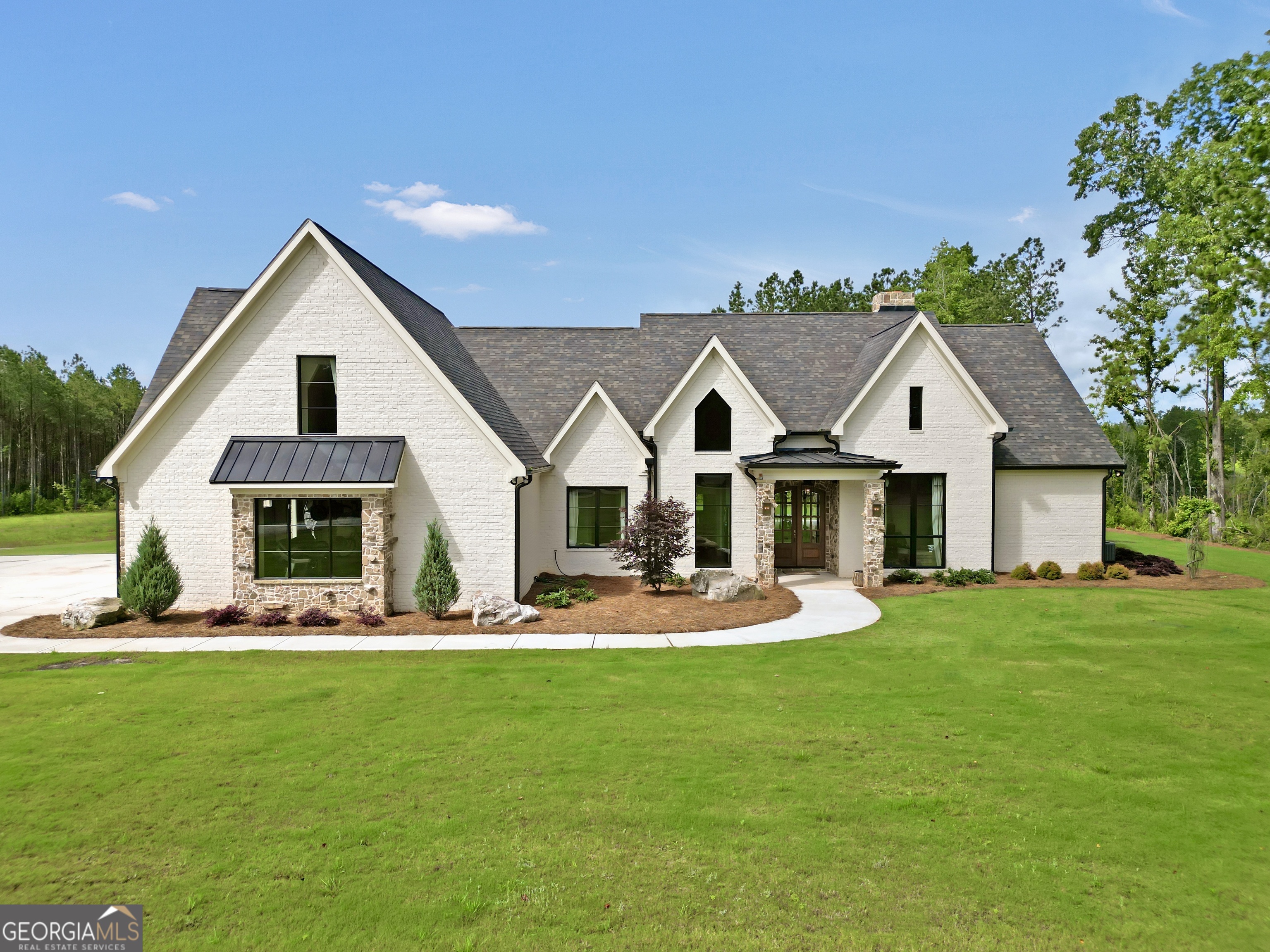 Tucked away in complete privacy, this exceptional 5,430-square-foot, 5 bedroom, 5 bathroom French Country estate captures the essence of refined countryside living in Monticello, Georgia. Set on 105 acres of gentle rolling hills and pretty woodlands this property is a rare blend of extraordinary elegance, modern comfort, and natural beauty. The home's exterior is a picturesque nod to classic French architecture, with a stone and brick facade, steeply pitched roofs, copper accents, and charming landscaping. Inside, the craftsmanship is immediately evident- Soaring ceilings with so many exquisite details; where every hard surface has been sealed with non-toxic sealant and all interior paint is Low Voc, views of your gorgeous landscape through Quaker Quartz Luxury Windows, locally hand-hewn real Hickory floors, Travertine Matte Porcelain Tile in the laundry & bathrooms, and grand Masonry fireplaces- with impressive stonework all hand cut and designed on site create an atmosphere of warmth and exclusive sophistication. The elegant kitchen features lovely real brick floors, stunning Zia Handmade Tile backsplash, Natural Oak soft close Cabinetry, genuine Copper sink + Copper cabinet pulls from the UK. The hidden Butlers Pantry offers beautiful shelving & room for an extra fridge and freezer. Designed with both everyday comfort and entertaining in mind, the kitchen blends seamlessly with the large dining space and living room offering space for intimate family meals & cozy movie nights and entertaining a large crowd. The living room boasts a feature wall of hand cut and crafted stone with a real Hardwood Mantle surrounding the masonry fireplace. Located on its own side of the home, The Master Suite is a luxurious retreat, offering divine privacy and space. From the soaring ceilings to the giant His & Hers closets, this space is sure to make you feel comforted and affluent. The en-suite bath features beautiful Walnut-stained double doors, white Cast-Iron free-standing tub and lavish bronze fixtures, stunning Zia Handmade Tile Master Shower, and His & Hers vanities. Across the home, past the Sound-Proof Home Office, you'll find the grand hallway (also soundproof) where there are 3 more bedrooms and 2 full bathrooms with beautiful luxury wallpaper. Venture upstairs to the giant 5th bedroom/guest suite with its own brick bathroom. Past the upstairs suite there is a large bonus room with a precious reading nook ideal for a media lounge, hobby studio, or kids hangout/play space. Venture further to the upstairs Family Room featuring its own Masonry Fireplace with Herringbone details + another full bathroom. You'll also find ample attic storage space, easily accessed through stylish doors. Outside you'll find so many unique activities, your home will become the cornerstone of entertaining and sweet memories for years to come. Wander, ride or exercise on over 7 miles of manicured trails reaching every corner of the property with multiple creek crossings. Within those trails, starting in the backyard- you have a Professionally designed 18-Hole Disc Golf Course. If you fancy a workout, the garage has been transformed into a Professional gym complete with tall mirrors, fans and Olympic Grade Flooring. A unique hidden feature of this home is the Rock-Climbing Wall located on the exterior of the garage. Dine alfresco, relax or entertain on the Veranda overlooking it all. Important to note: the whole home has instant hot water & top-of-the-line water filtration system on the well. The well is 600ft deep & pumps 7 gallons per minute. There is an auto controlled irrigation system in the yard. In this home, luxury is an experience all around. Do not miss this remarkable, one-of-a-kind home!!