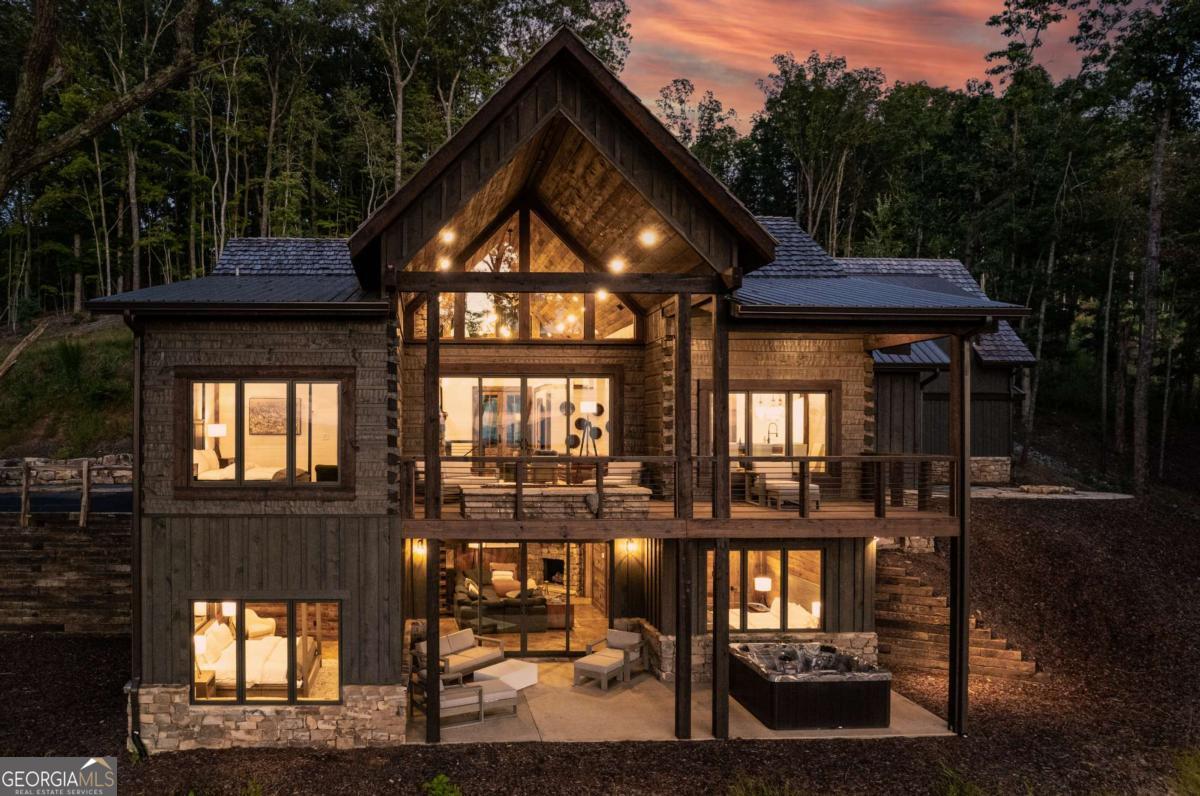 Discover elevated mountain living in this newly built luxury home just 15 minutes from downtown Blue Ridge, where panoramic views and refined design create the perfect year-round escape. The main residence includes three king ensuite bedrooms, each with spa-style baths and premium finishes, plus a detached guest loft featuring custom twin-over-twin and queen-over-queen bunk beds-ideal for guests or rental flexibility. The open-concept great room is anchored by a floor-to-ceiling stone fireplace, vaulted ceilings, and expansive windows that frame the mountain landscape. A chef's kitchen boasts high-end appliances, a large island with seating, and a mountain-view dining area. Multi-level decks offer premium outdoor living with a lava rock fire pit, hot tub, and lounge areas perfect for entertaining or quiet sunsets. A detached game garage includes a pool table, ping pong, and media setup. Designed with luxury and comfort in mind, the home features wide plank flooring, designer lighting, and high-speed internet. Located near top destinations like Old Toccoa Farm Golf Course, Ron Henry Horseshoe Bend Park, the Mineral Bluff Depot, and Appalachian Trail Rides, this property offers the ultimate North Georgia lifestyle. Whether you're seeking a high-end full-time residence, second home, or income-generating retreat, this exceptional property is a place to live, work, and play without compromise.