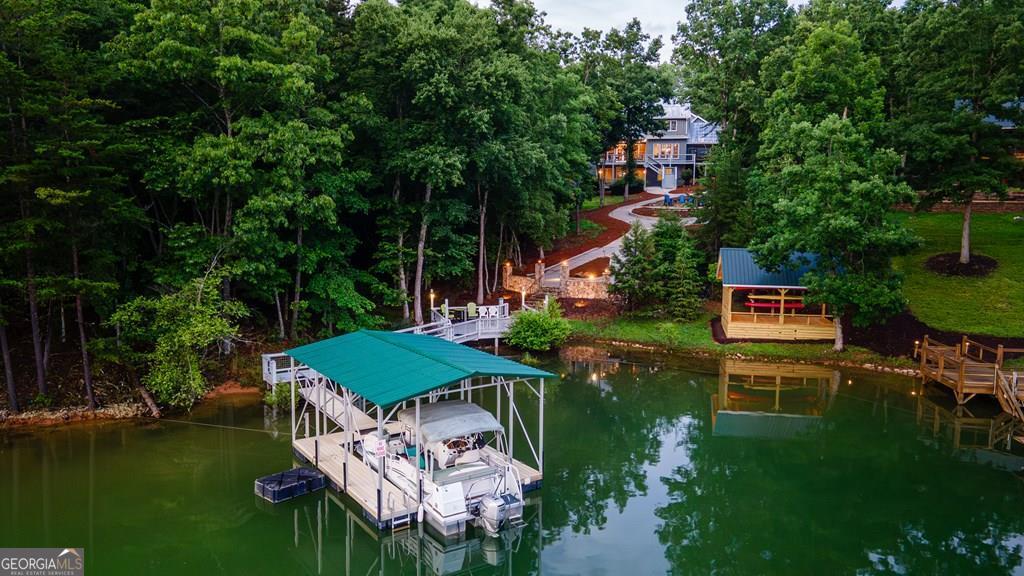 Welcome to the ultimate Lake Nottely retreat! A perfect match if your style is luxury and your vibe is laid-back lake life. Nestled in a peaceful cove with a private and permitted dock ready for your pontoon, this exceptional home is designed for making memories-whether you're boating all day or enjoying a glass of wine on the screened-in porch at sunset. Step inside to a warm, elegant interior featuring hardwood floors, oversized living spaces, and a true gourmet kitchen-complete with a 6-burner gas range, double ovens, custom cabinetry, granite island, additional prep space with sink, and a commercial-grade hood built for the serious home chef. The expansive primary suite is a haven, offering lake views, a large sitting area, and the primary bath boasts a garden tub, walk-in tile shower, and double vanity. Each bedroom has a private bath, and main and upper floor bedrooms all have walk-in closets, perfect for guests and family alike. The half bath is conveniently located on the main level. Entertainment and comfort are everywhere-from the custom bar with kegerator and game room with walk-out access to one of the multiple decks. The outdoor space is tailored for grilling, gathering, or just soaking up the mountain air. Should you need even more space, the finished room over the garage is well suited for extra sleeping quarters, hobby space, or storage. Outside, a colorful custom Compass Rose stamped into the concrete sets the tone of creativity and charm. Use the Gator to run firewood down to the lakeside fire pit or haul the tubes up after a day on the water. Storage is abundant with easy access and walk-in attic space as well as two full basement rooms, one perfect for a workshop. This home isn't just a house-it's a lifestyle for those who love to relax, entertain, and explore. Luxury, leisure, and lake life are calling. Come see what your next chapter could look like.