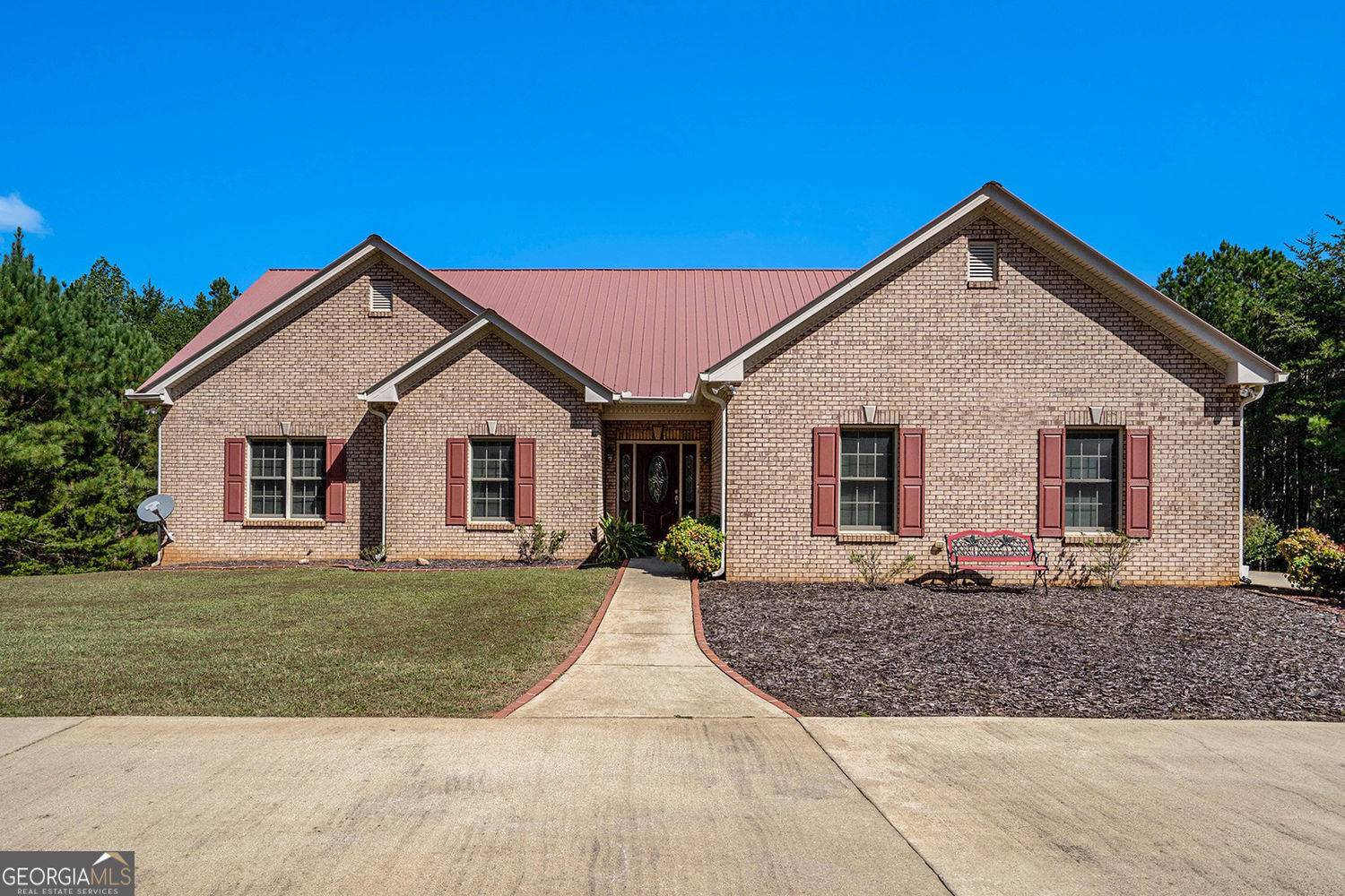 This well-built four-sided brick ranch is set on over 10 acres of serene, wooded land. It's only a few minutes from the lovely downtown Ball Ground. This home prioritizes comfort and accessibility. It includes wide hallways and doorways on the main and terrace levels. Step inside to find freshly painted interiors and gleaming hardwood floors throughout the main level. The foyer opens to a cozy living room anchored by a classic brick fireplace, which flows seamlessly into the dining room. A light-filled sunroom just off the living room is perfect for enjoying your morning coffee or winding down in the evening. Step out onto the back deck and take in serene views of the lush, private backyard. The kitchen offers stained wood cabinetry, a breakfast bar, and direct access to the two-car garage. A nearby laundry room includes upper cabinets for additional storage. The primary suite features an ensuite bath with a separate soaking tub and shower. Two additional bedrooms on the main level share a full bath. The terrace level offers fantastic options for an in-law suite. It features a large family room, an oversized bedroom, and a full bath. Plus, there's a unique beauty shop area, a flex room, and a second laundry space. A private entrance and patio add convenience and comfort for guests. An additional sunroom and unfinished storage complete the lower level. The property is zoned agricultural. It offers many chances for peaceful living and space to grow. There is long road frontage so there is opportunity to subdivide.