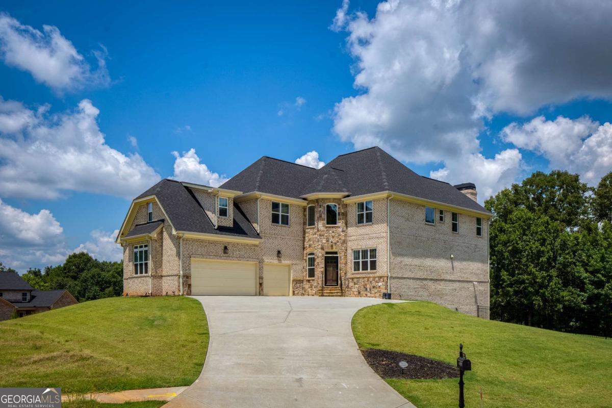 Exquisite Luxury Estate in Prestigious Champions Park where elegance, comfort and sophistication converge in this magnificent 6-bedroom, 5-bathroom estate. Nestled on a coveted corner lot, this home features a fully finished basement and an array of upscale amenities tailored for refined living. Experience the interior elegance as you step through the grand two-story foyer onto timeless hardwood floors that guide you through the main level's open, sunlit spaces. A formal living room for entertainment, while the luxury dining room-enhanced by a custom accent wall that adds style to every gathering. The gourmet kitchen is a culinary dream, featuring sleek white cabinetry, oversized center island with built-in microwave, gas cooktop, wall oven, and high-end appliances next to the spacious breakfast area with views of the family room. Enjoy seamless indoor-outdoor living with access to a walkout patio and fenced backyard perfect for relaxing or entertaining. A main-level guest bedroom with a full bath offers privacy and ease for visitors or multi-generational living offering both comfort and functionality. Upstairs, the expansive primary suite includes a serene sitting area, spa-inspired ensuite with soaking tub and separate shower and custom-designed walk-in closets. Three additional bedrooms and two full baths complete the upper level; each thoughtfully designed with ample space and storage. The fully finished terrace level serves as a private guest or in-law suite, featuring a bedroom and full bath, kitchen, dining area and large family room with direct walk-out access to the immaculately landscaped fenced backyard. Spacious three-car garage with storage and dedicated EV charging outlet. This unbeatable location is just minutes to Camp Creek Marketplace, dining, shopping, Hartsfield-Jackson Atlanta International Airport, I-285 and major expressways, Woodward Academy and Atlanta's vibrant Intown district. This home blends prestige and convenience into one of South Fulton's most exclusive communities. Priced below market value, this is truly a "Must-See" Sunday 8/3 - 2-4PM. Showings begin Friday 8/1.